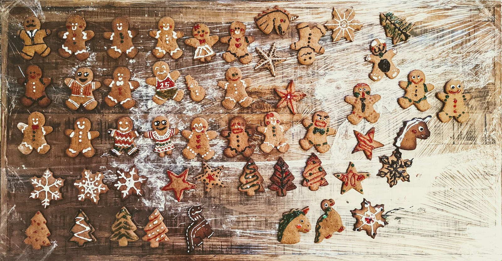 Rows of decorated gingerbread cookies on a floured table