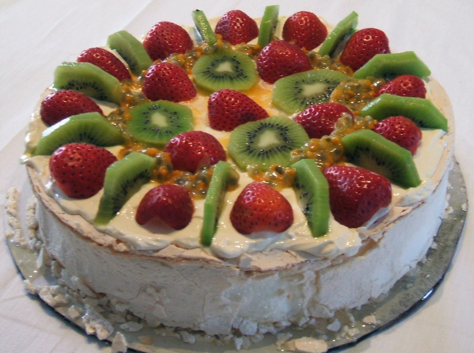 Pavlova topped with kiwi slices, strawberries and passion fruit