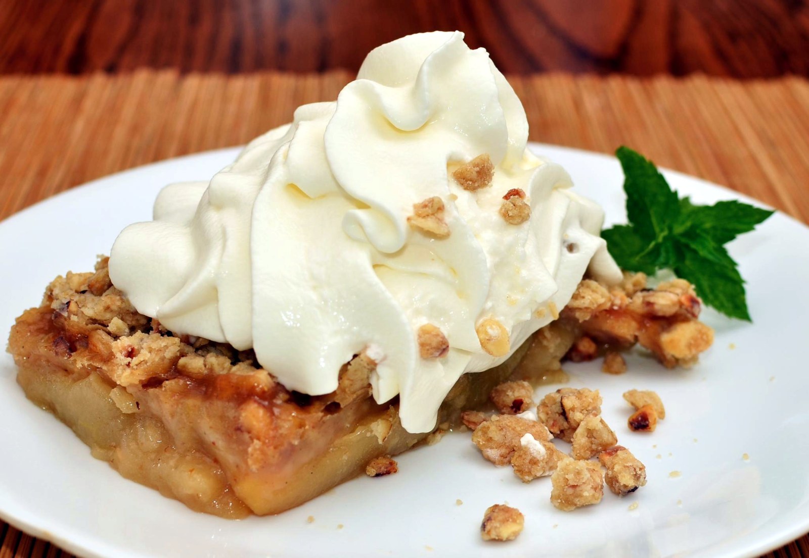 Warm apple crisp with whipped cream and crumble topping on a white plate