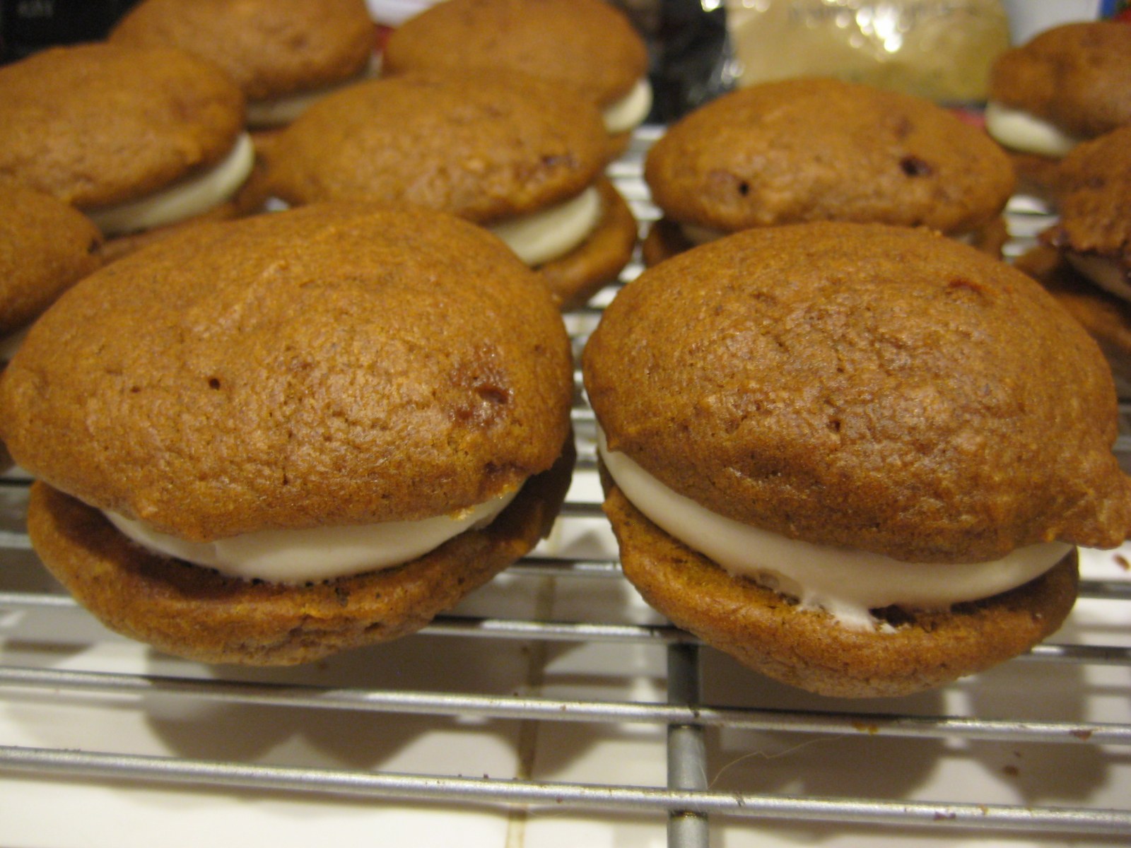 Pumpkin whoopie pies with cream filling on a wire rack