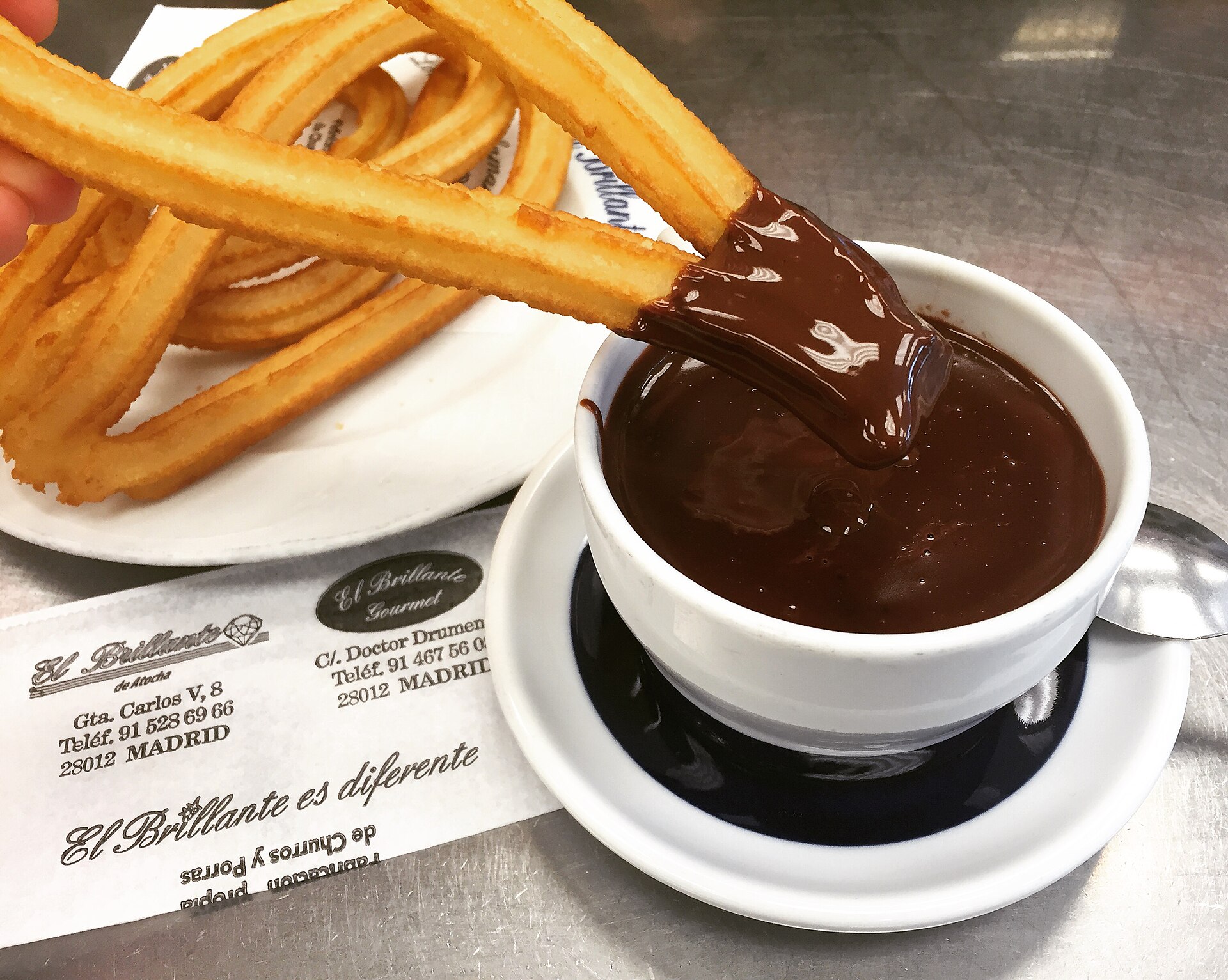 A churro dipped in a cup of thick chocolate