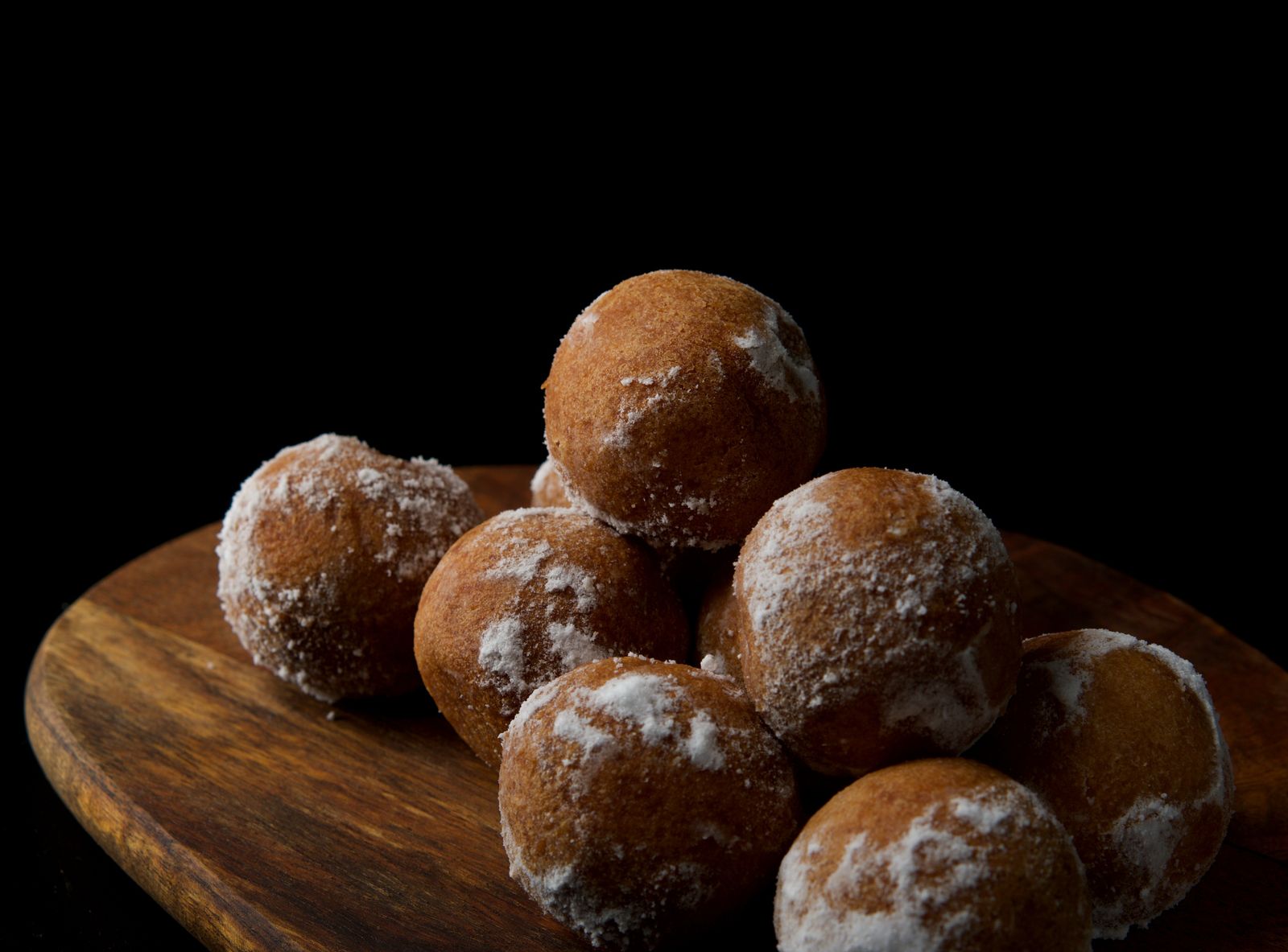 Sugar dusted donut holes on a wooden board
