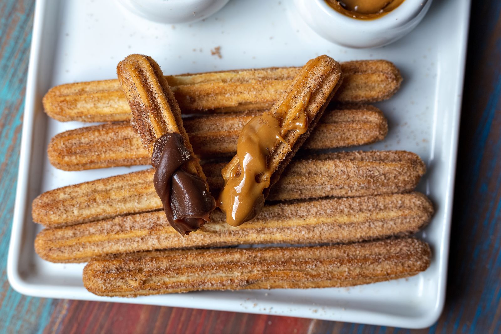 Churros dipped in chocolate and dulce de leche on a white tray