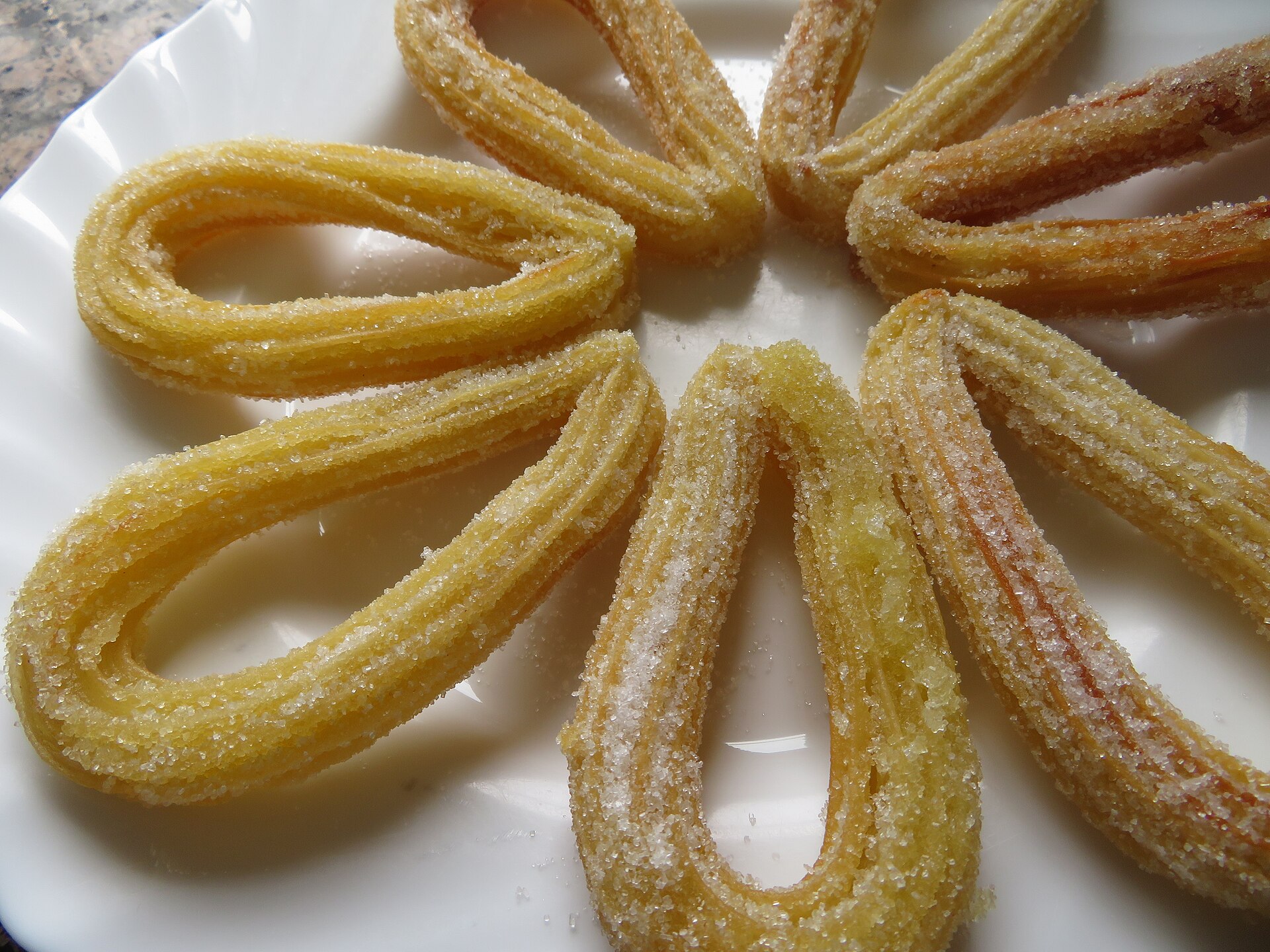 Churros piped in loops and arranged in a ring on a plate