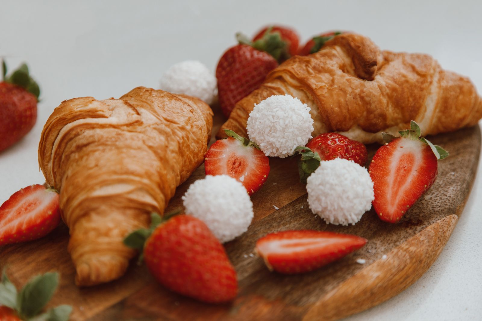 Fresh strawberries and flaky pastries on a wooden board
