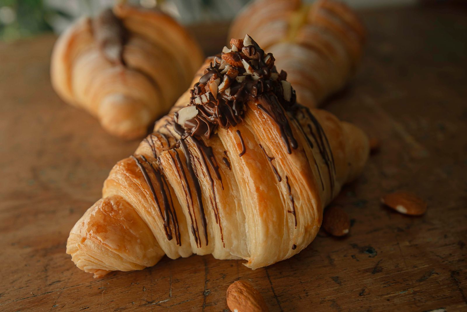 Croissant recipes: chocolate drizzled almond croissant on a wooden board