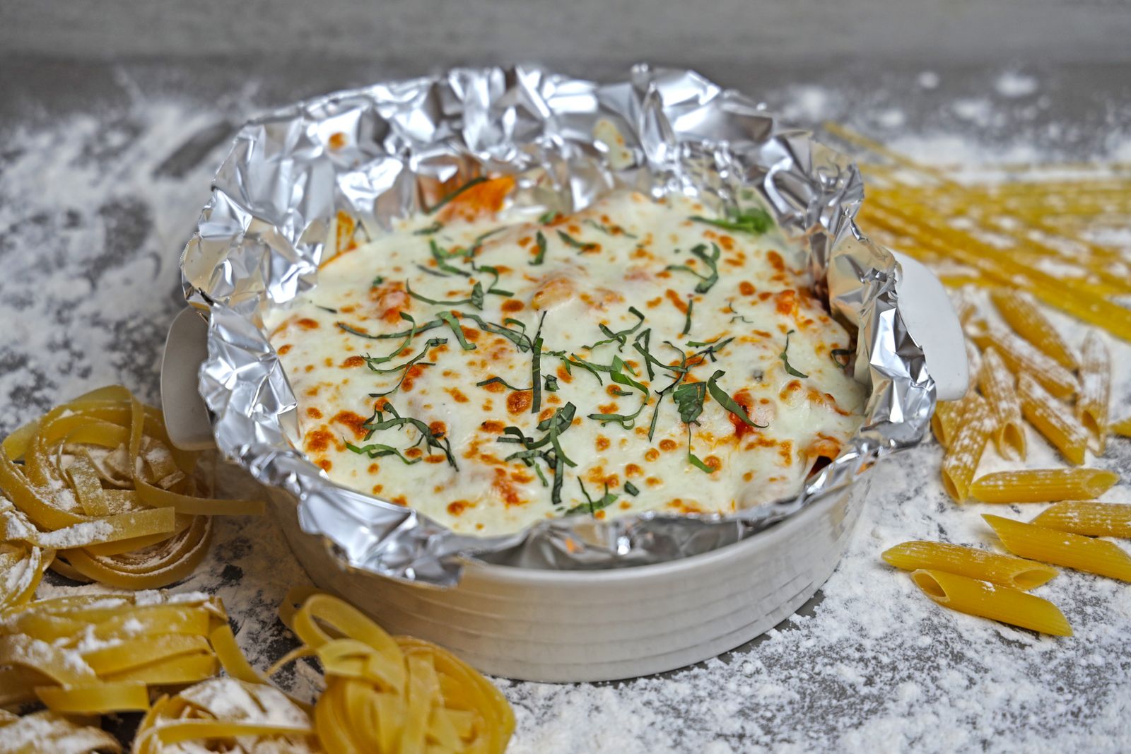 Chicken spaghetti casserole in a foil lined dish, ready to freeze or deliver