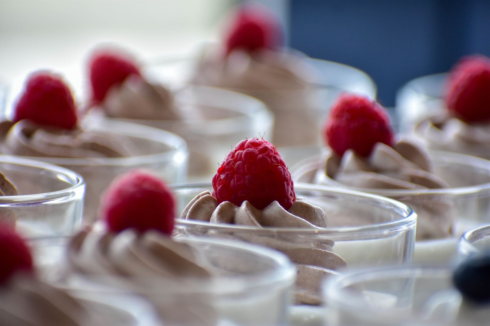 Classic chocolate mousse in glass cups topped with raspberries