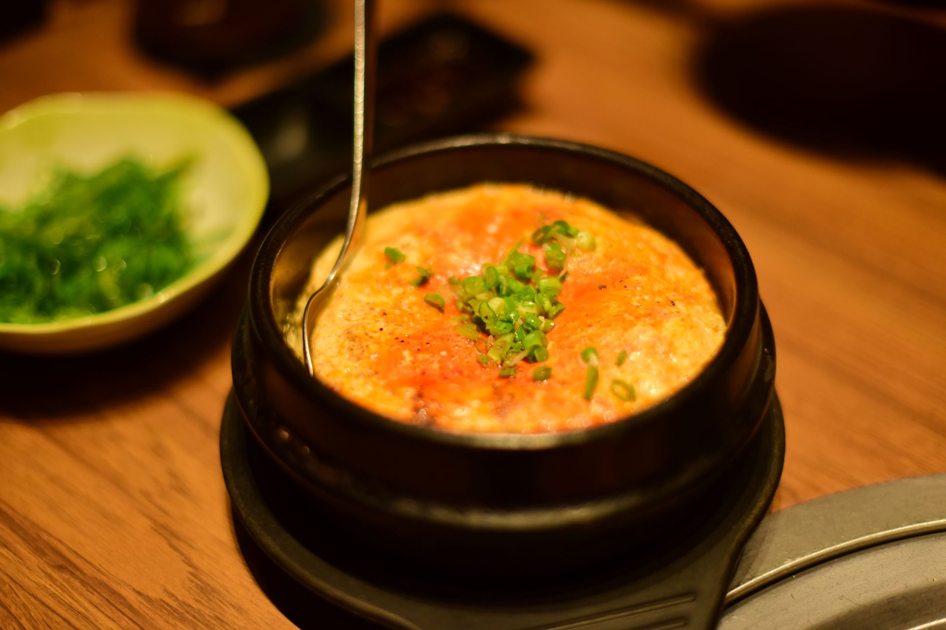 Steamed egg custard in a black pot with green onions