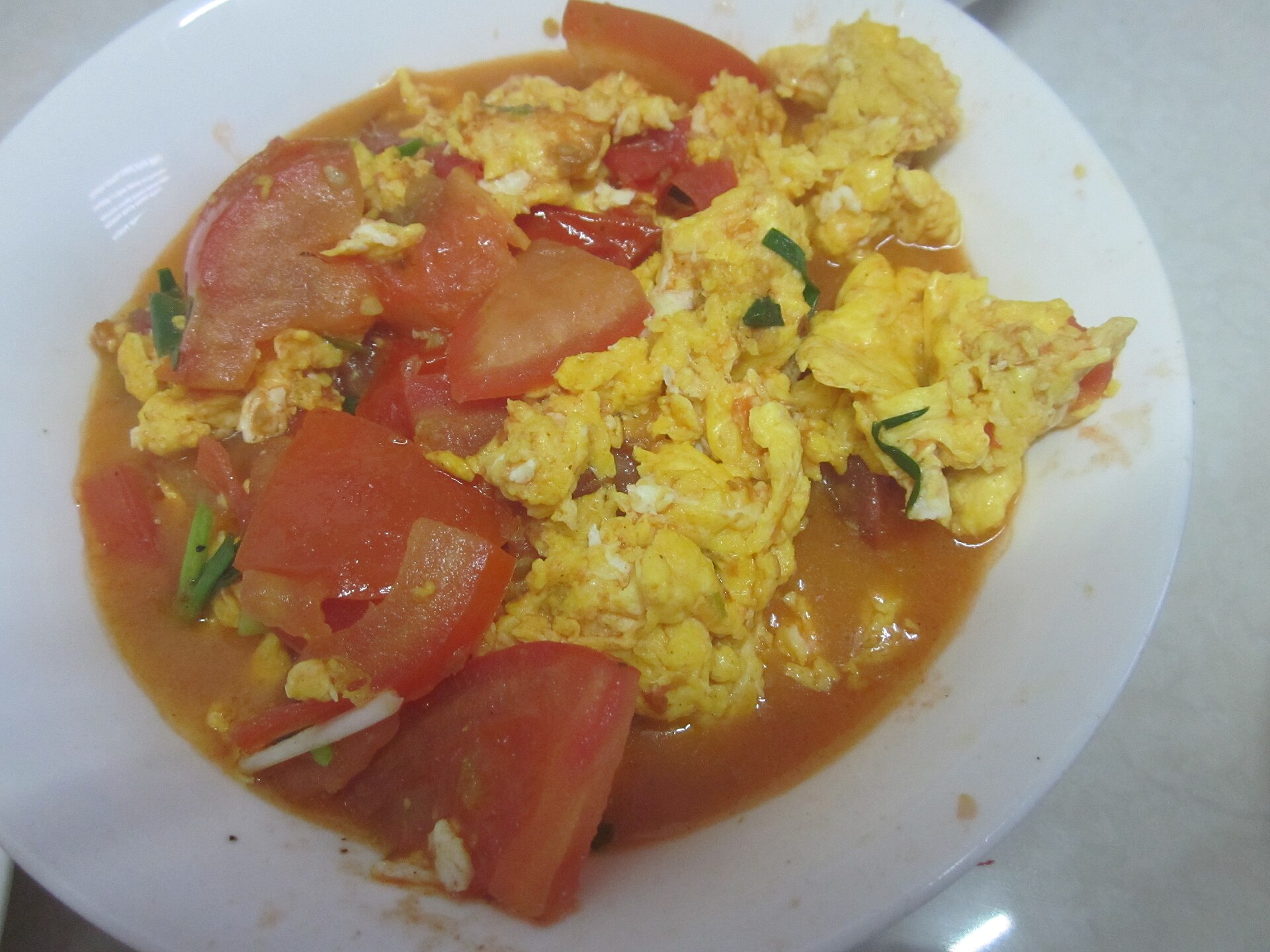 Stir fried tomato and eggs on a white plate