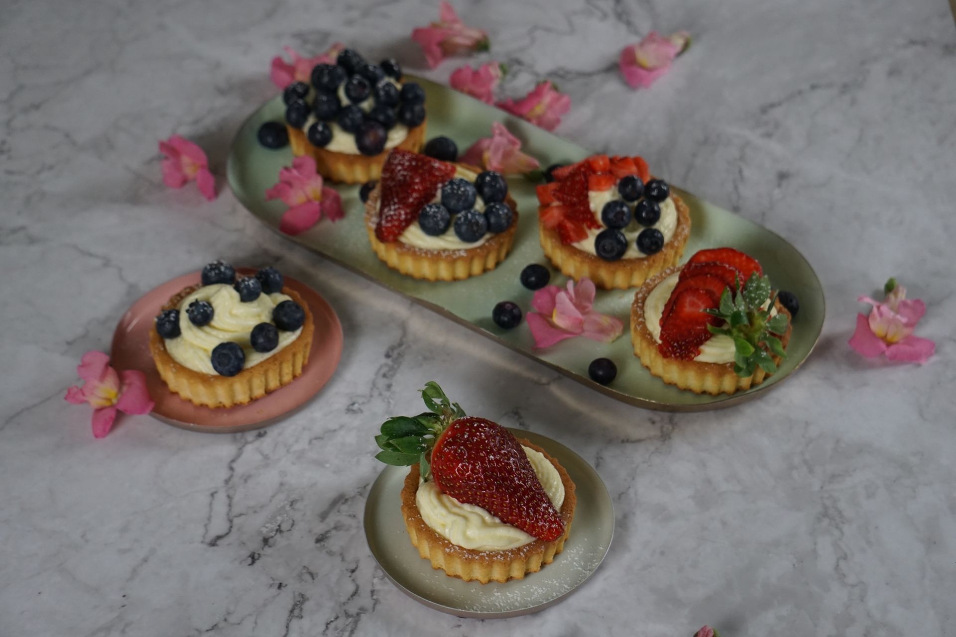 Berry tartlets with cream on a white tray