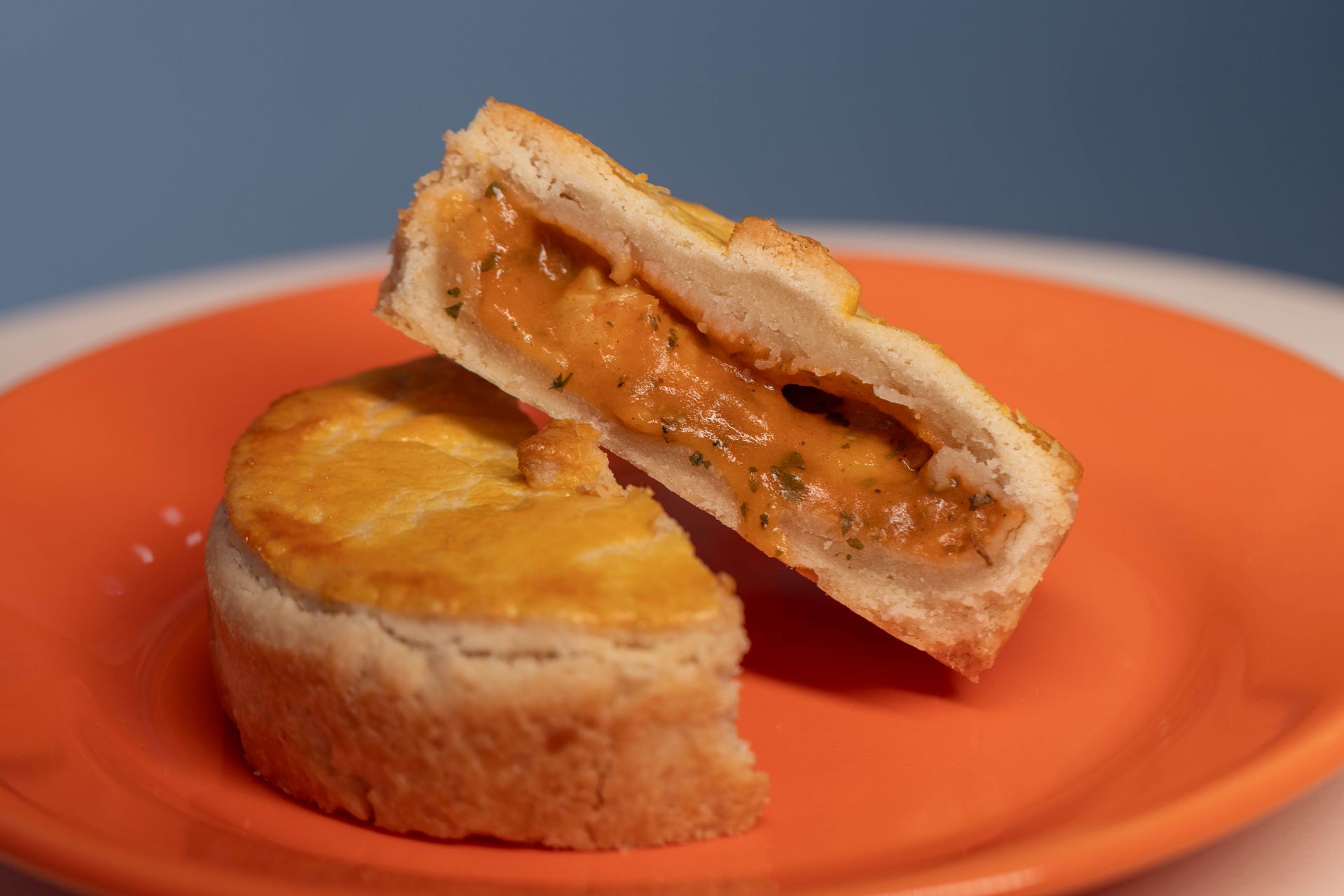 Golden pot pie cut in half on an orange plate