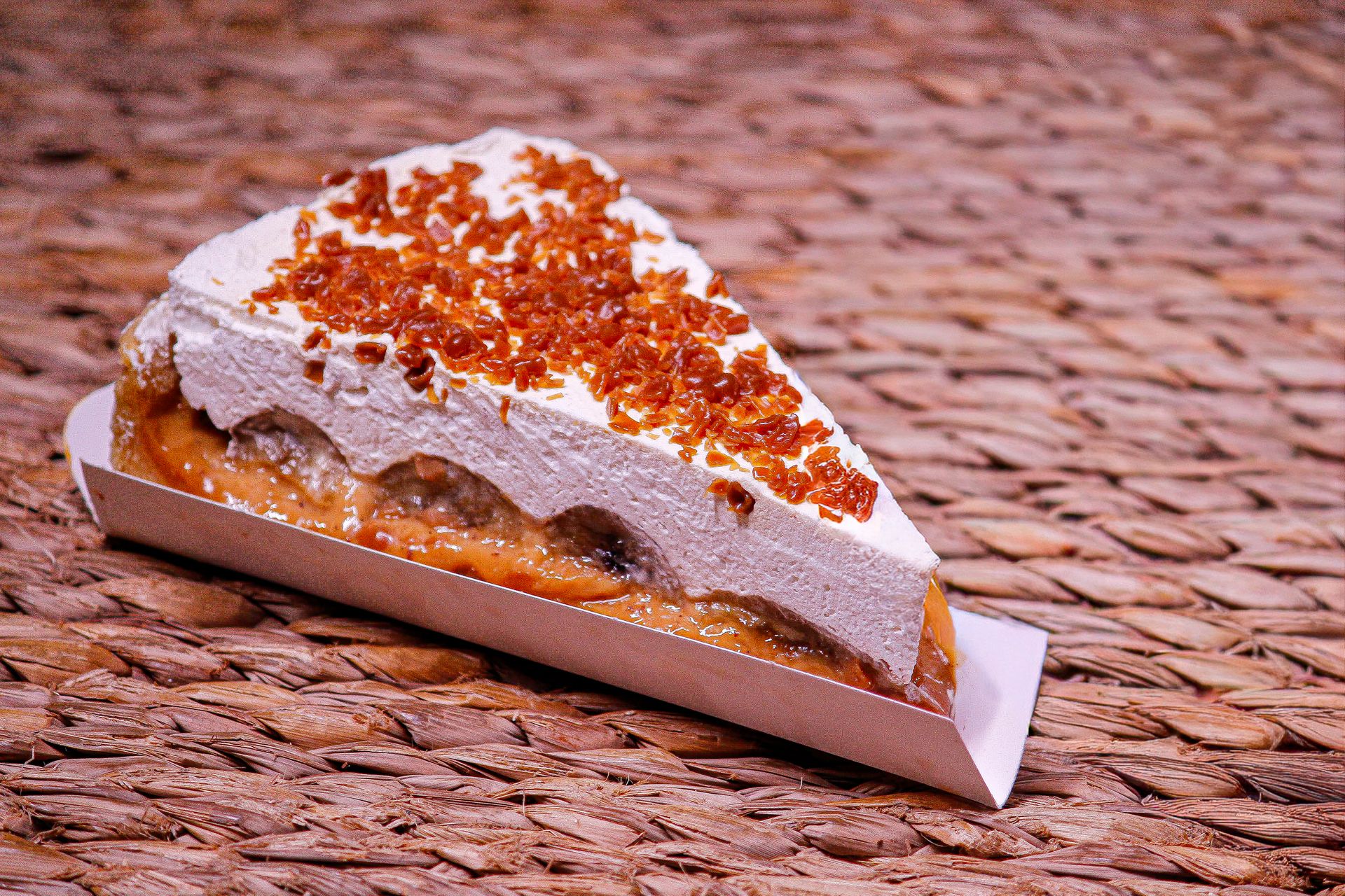 Slice of banoffee pie with cream and toffee crumbs