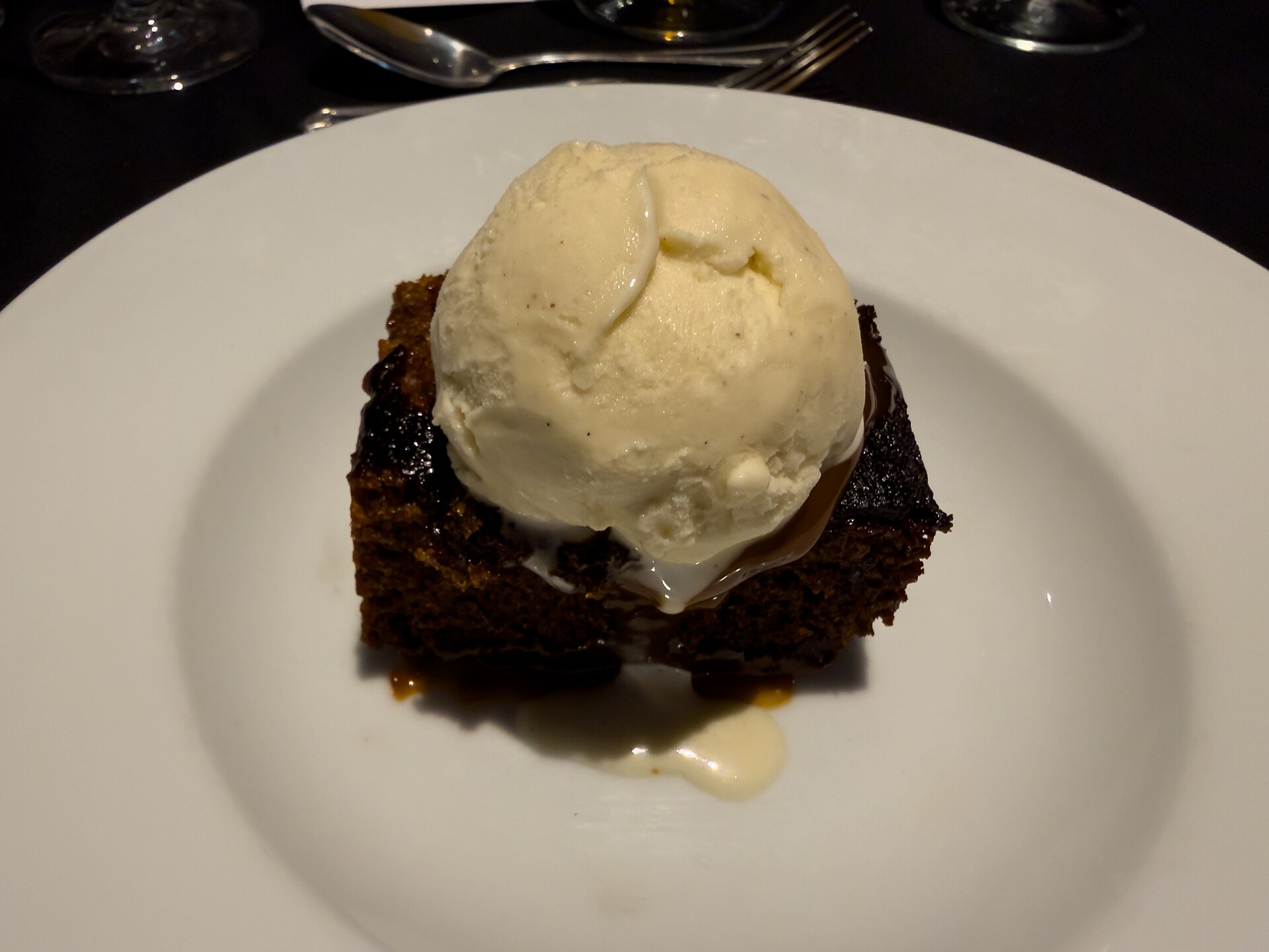 Sticky toffee pudding with pecans and a scoop of vanilla ice cream