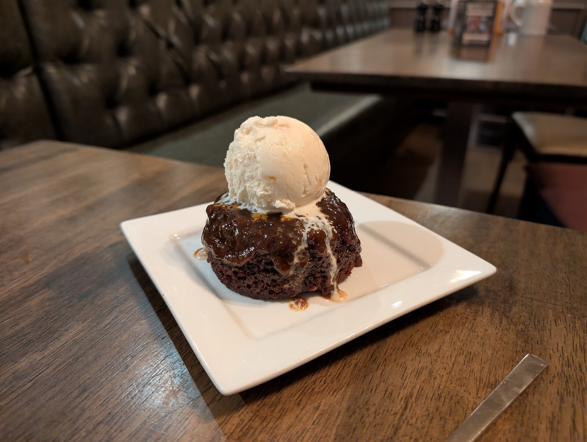 Date cake square with honeycomb ice cream on a white plate