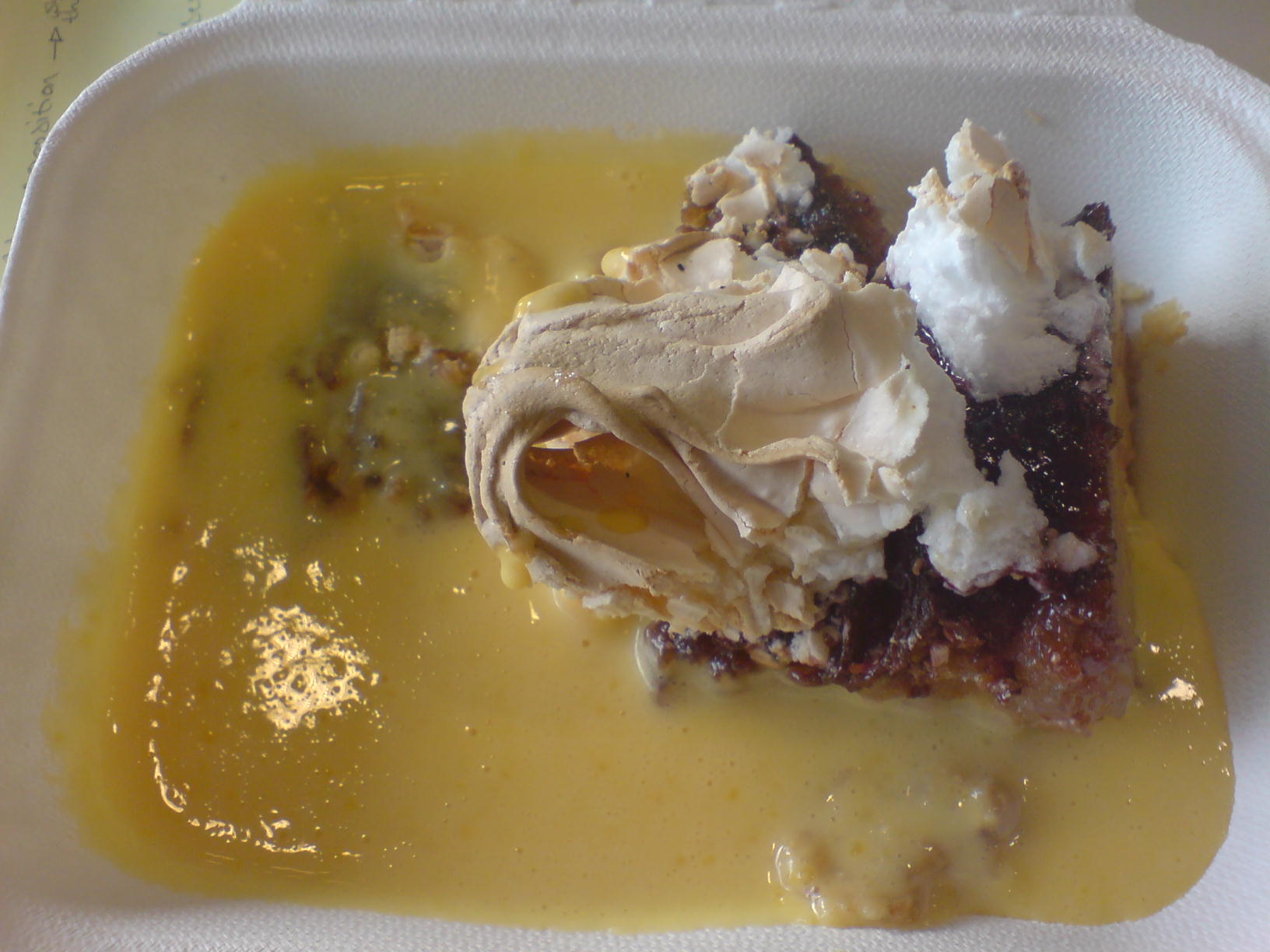 Queen of Puddings with meringue and custard in a bowl