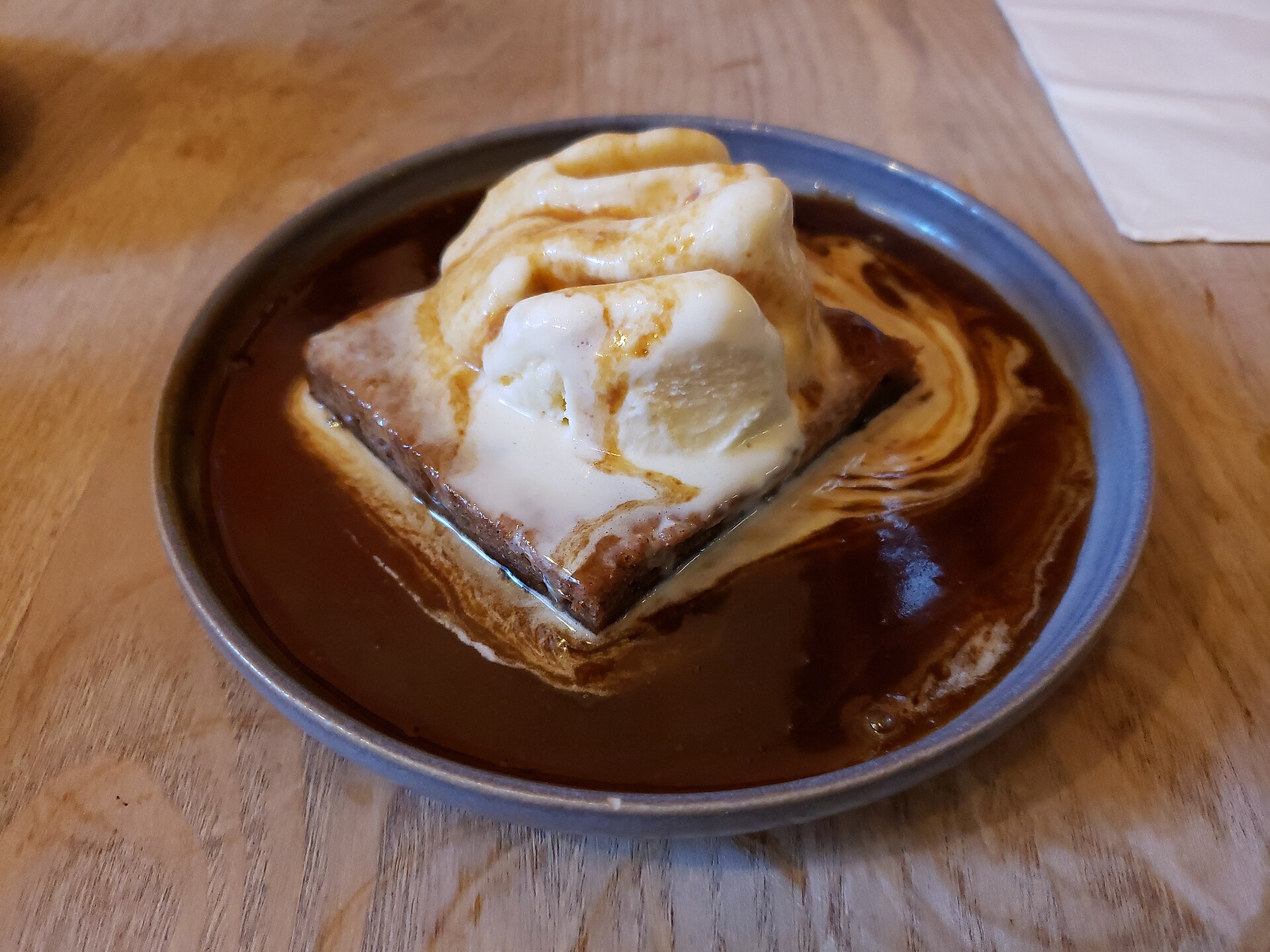 Sticky toffee pudding with ice cream in a pool of toffee sauce