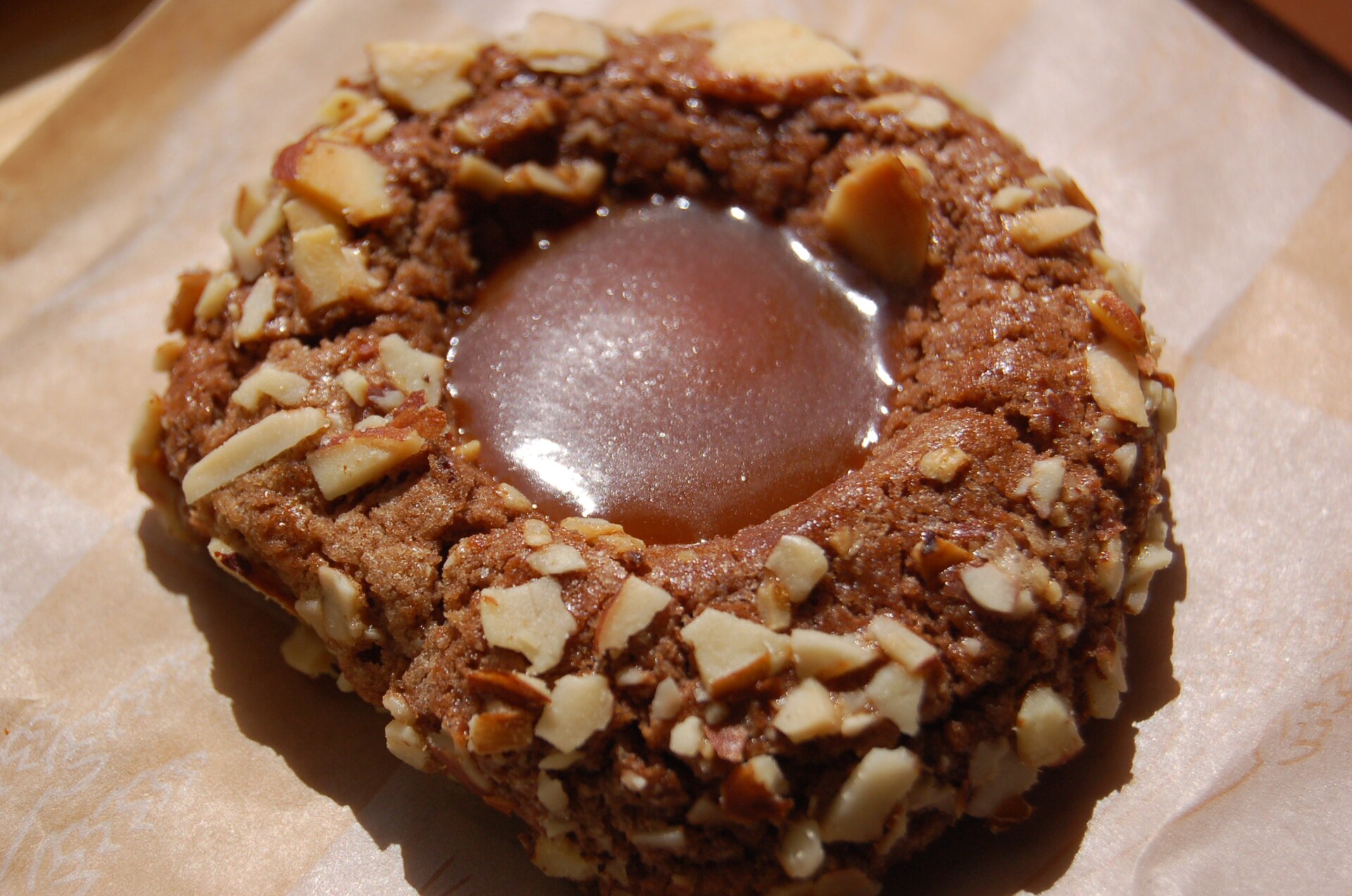 Chocolate thumbprint cookie rolled in nuts with a caramel center