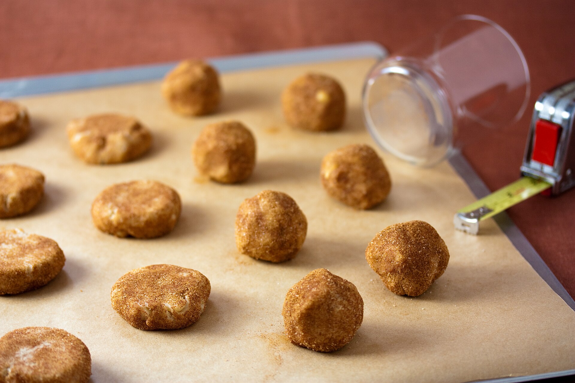 Rolled cookie dough balls on parchment ready for the cinnamon sugar
