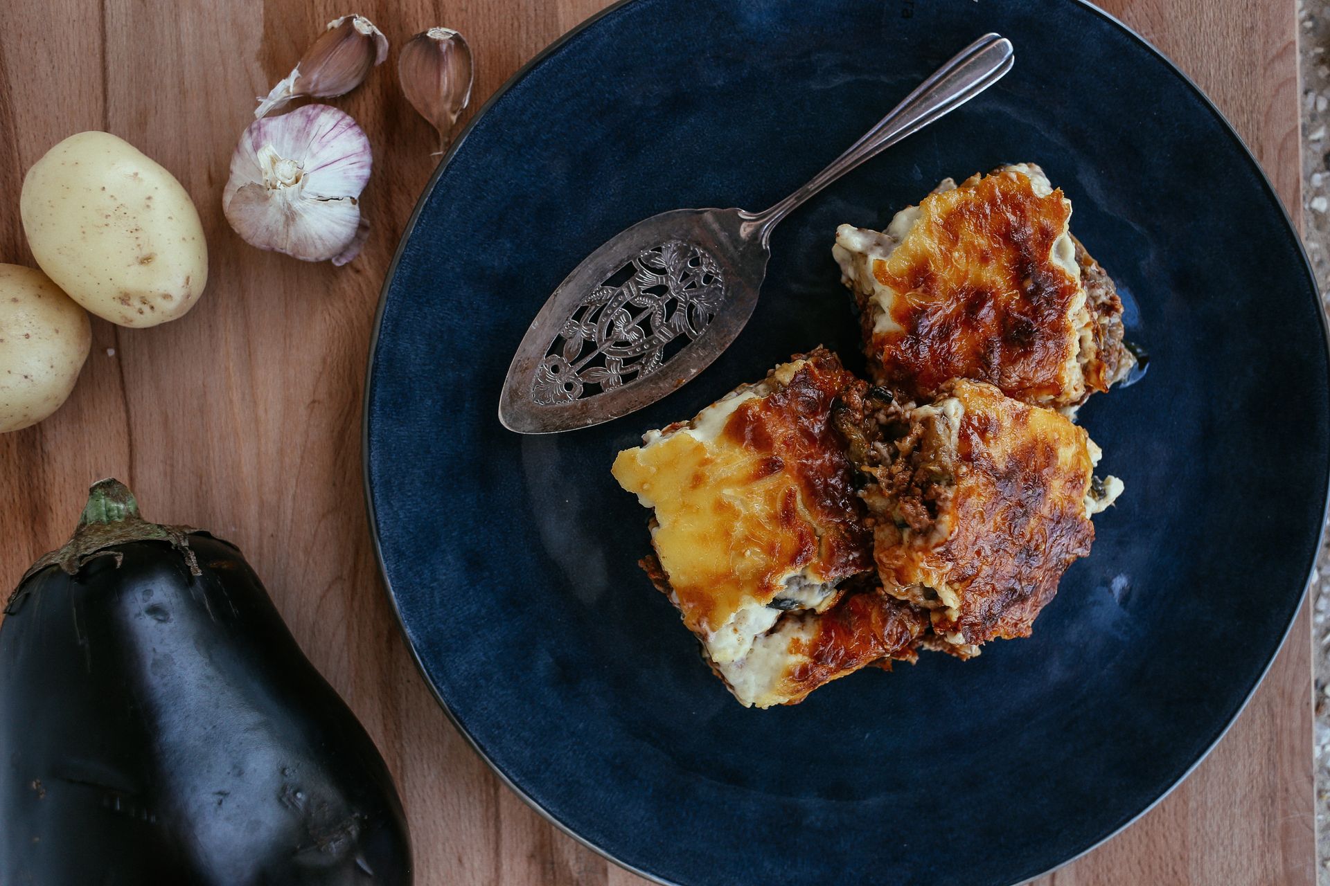 Eggplant lasagna pieces on a dark plate next to a whole eggplant