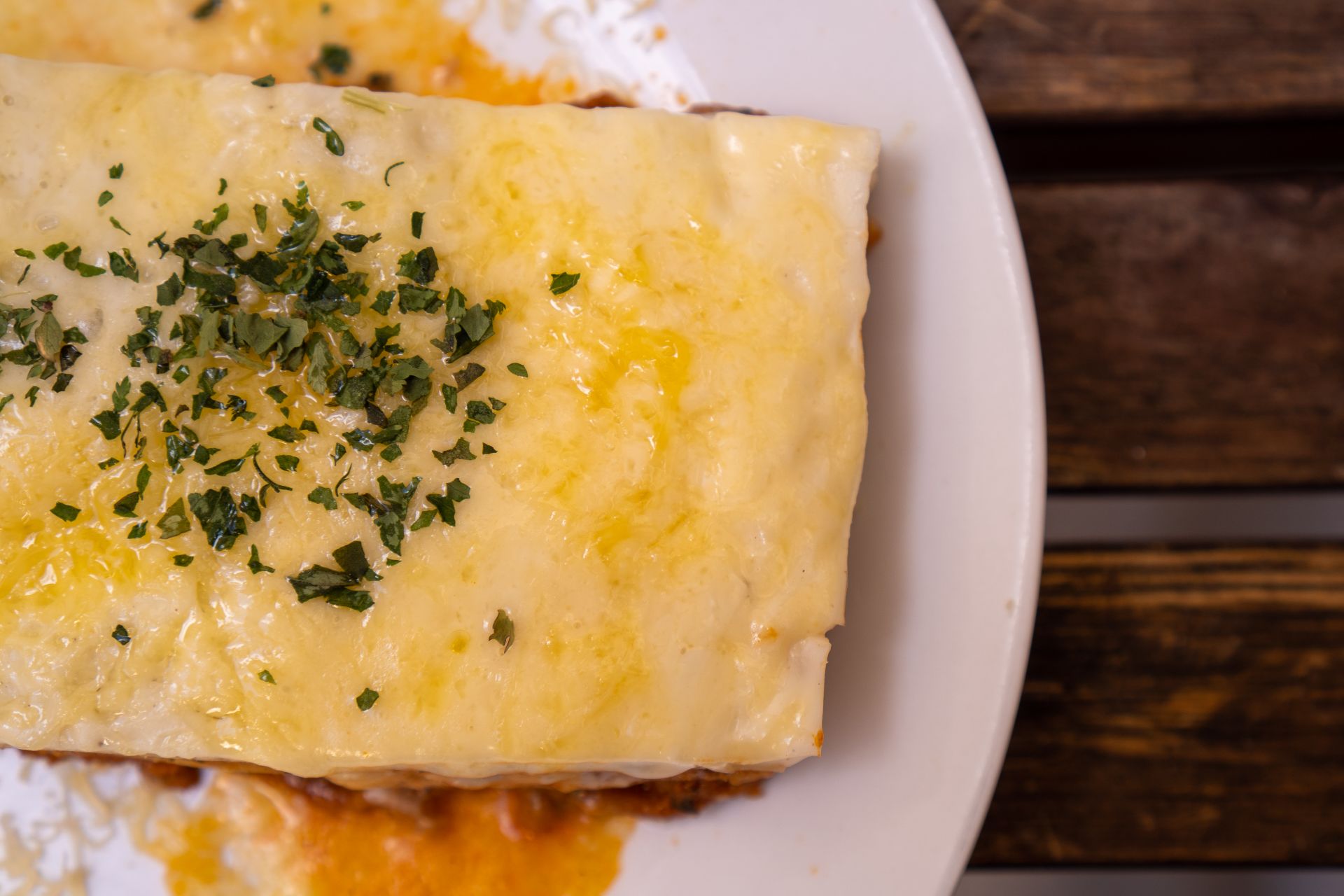 Close up of a golden cheesy lasagna top with herbs