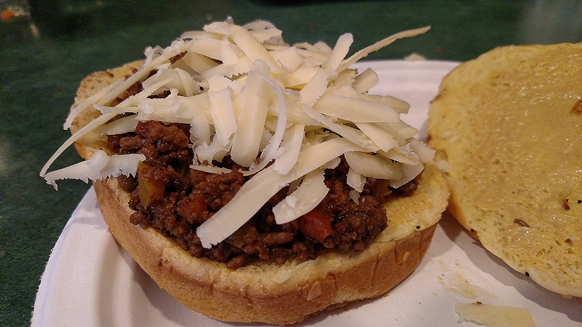 Sloppy joes topped with shredded white cheddar on a toasted bun