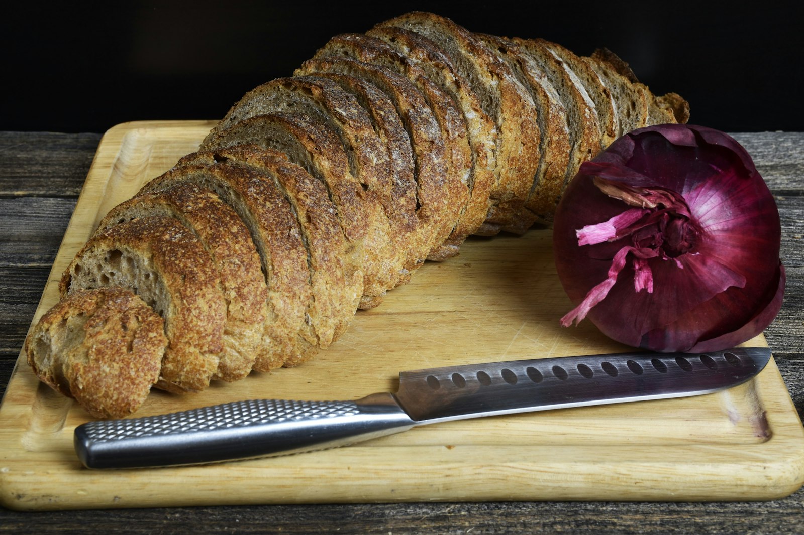 Whole baked loaf with a red onion on a cutting board