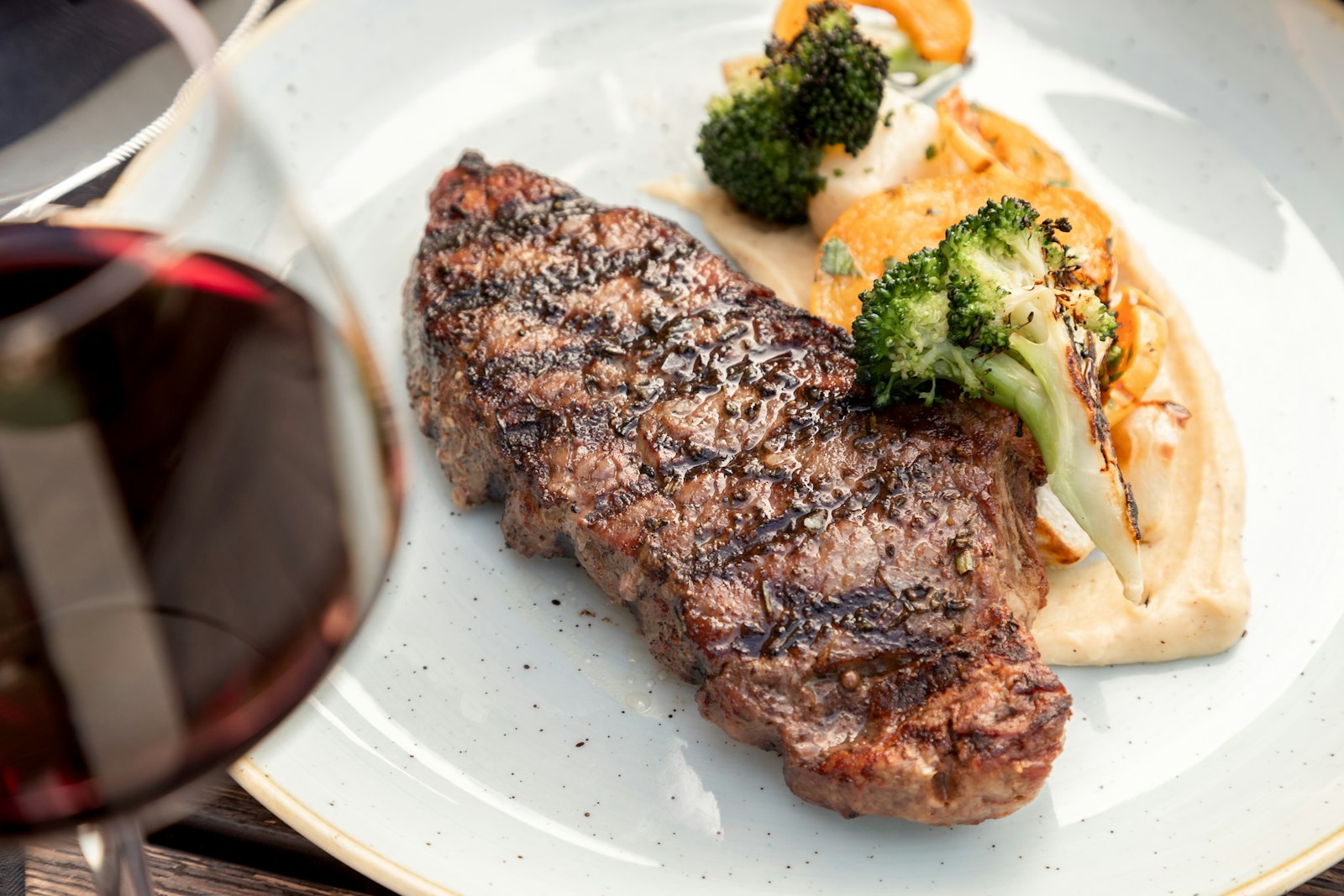 Seared steak with broccoli on a white plate