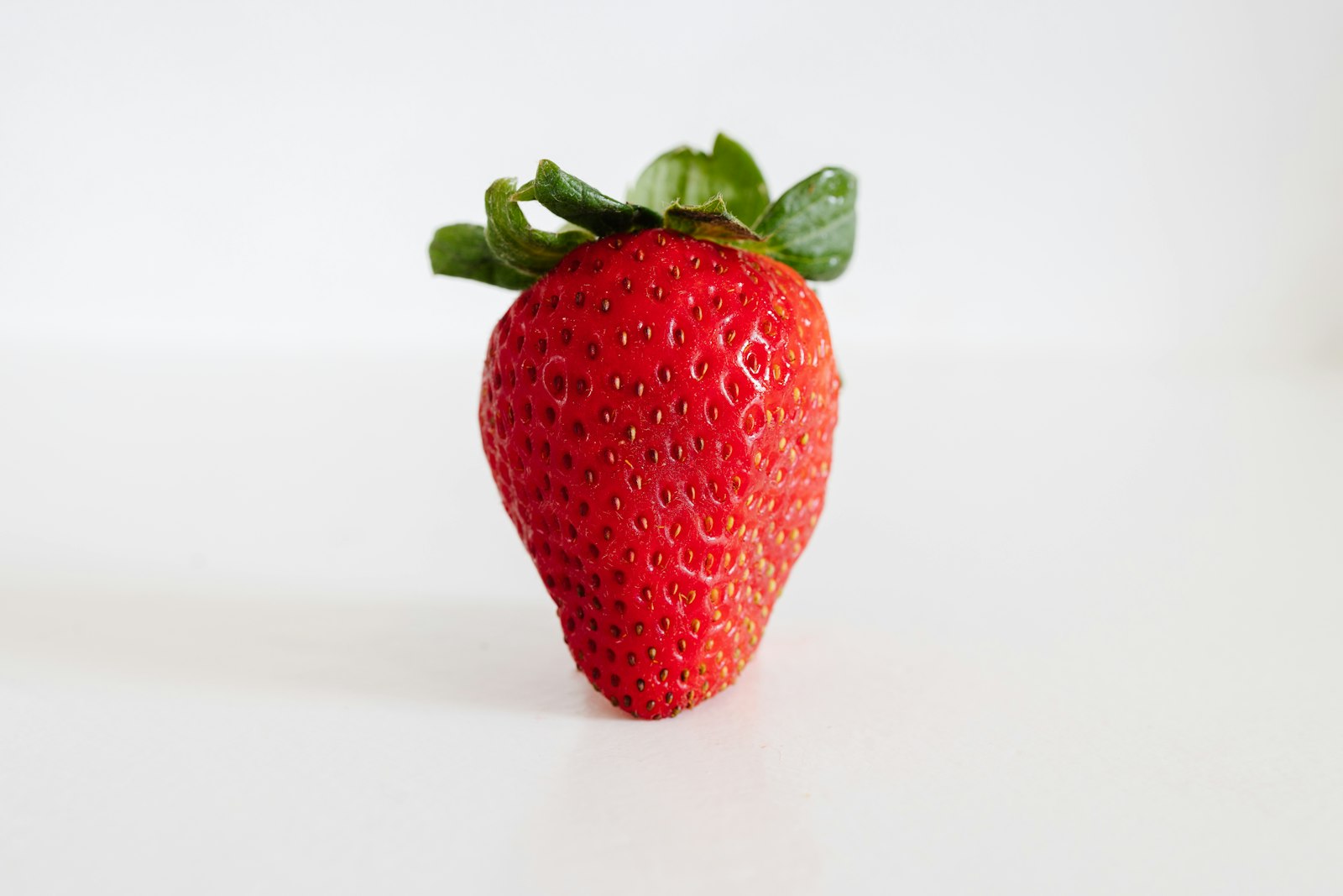Single ripe strawberry with its green top