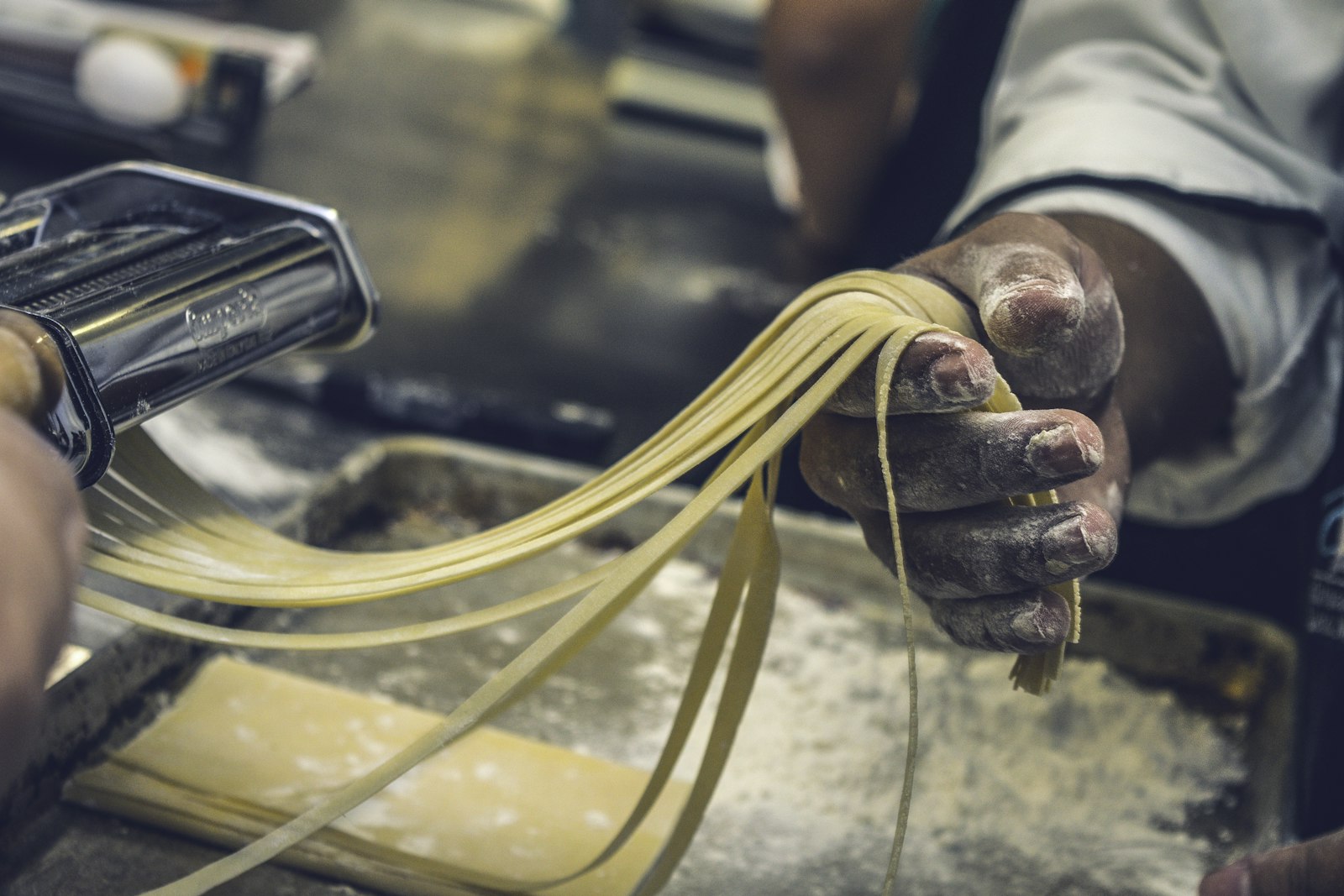 Hands pulling long fresh noodles by hand