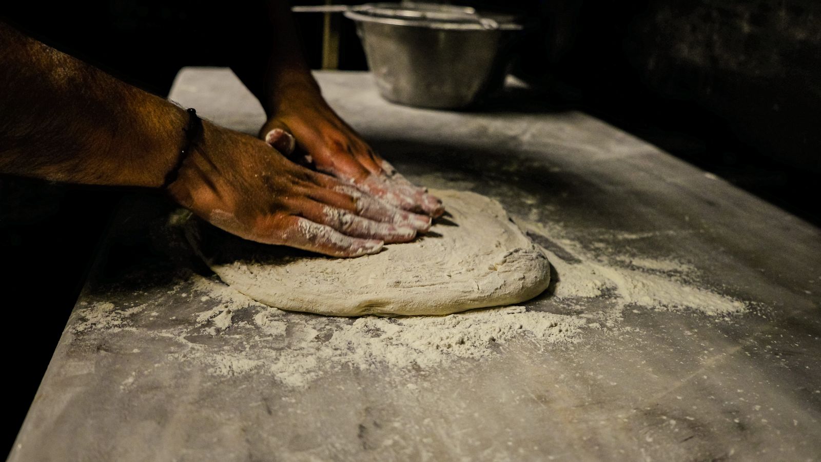 Hands kneading pasta dough on a floured table