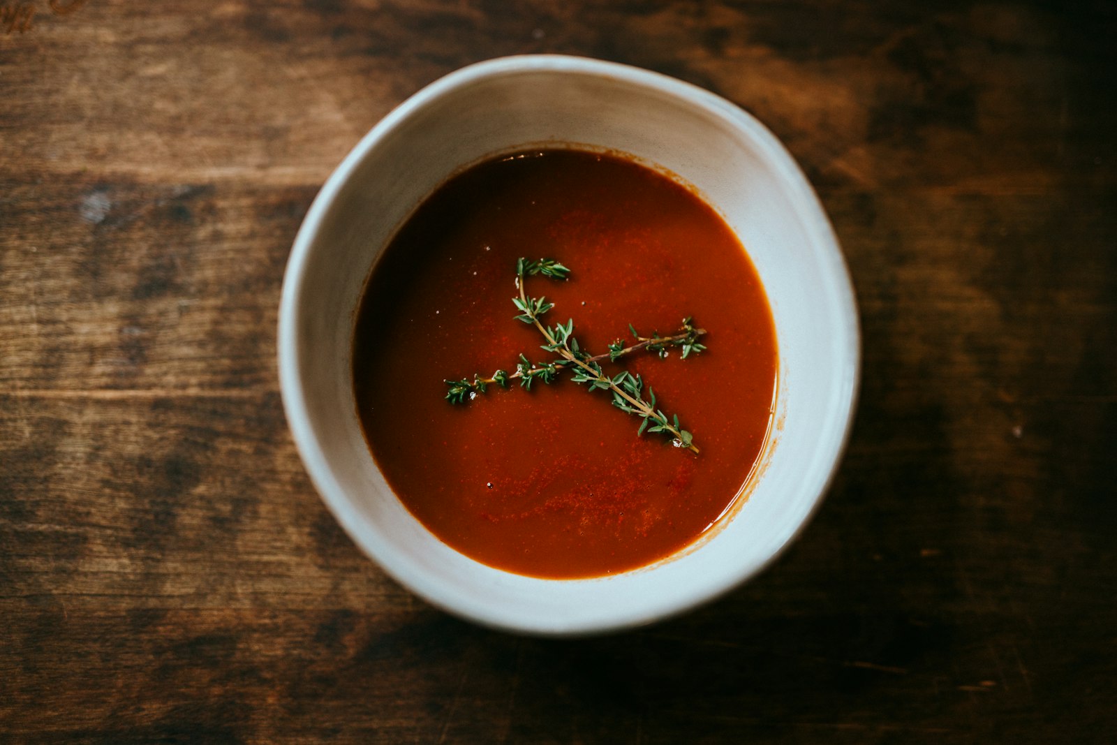 Slow cooker tomato soup with fresh thyme in a white bowl
