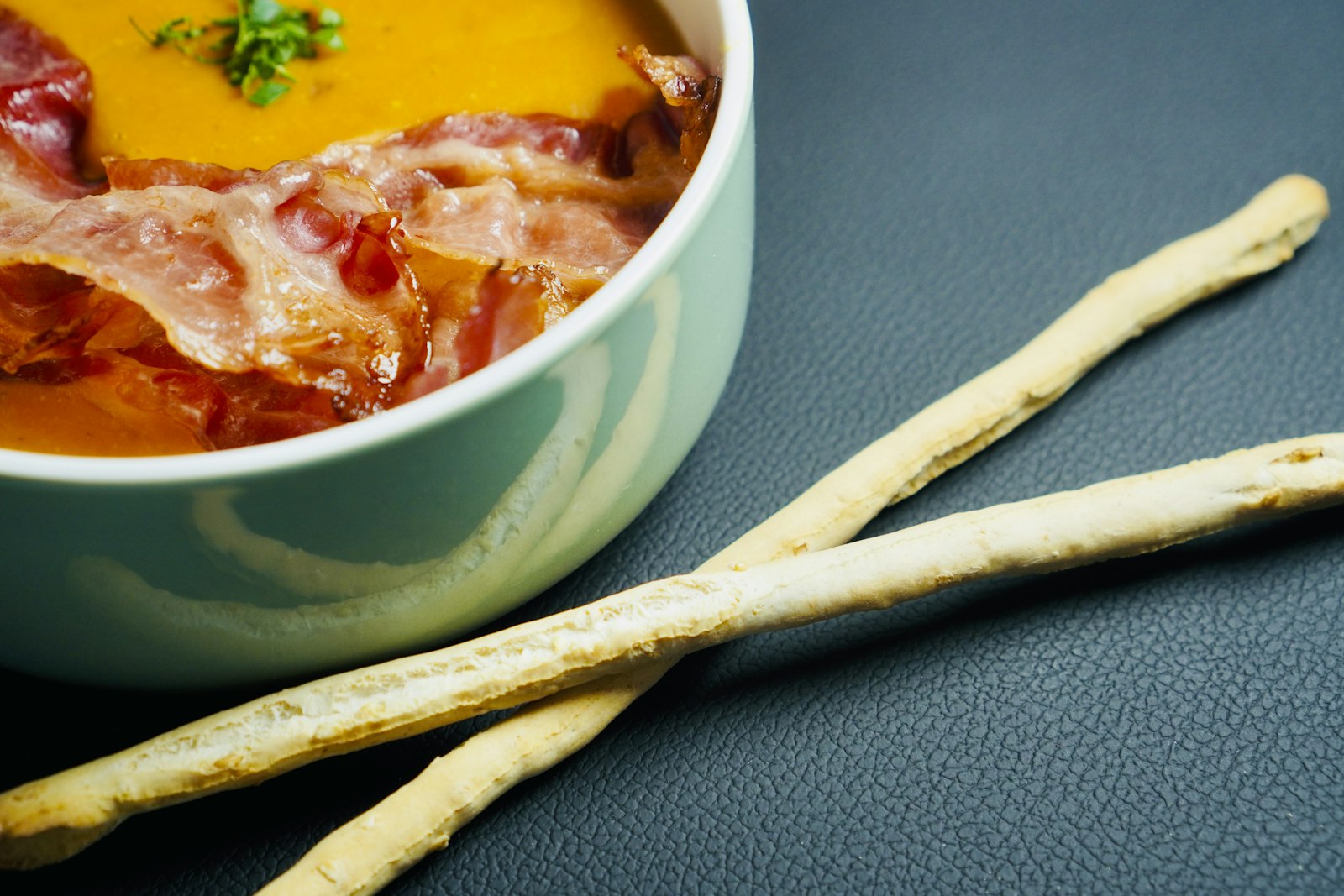 Smoky tomato soup topped with crispy bacon and breadsticks