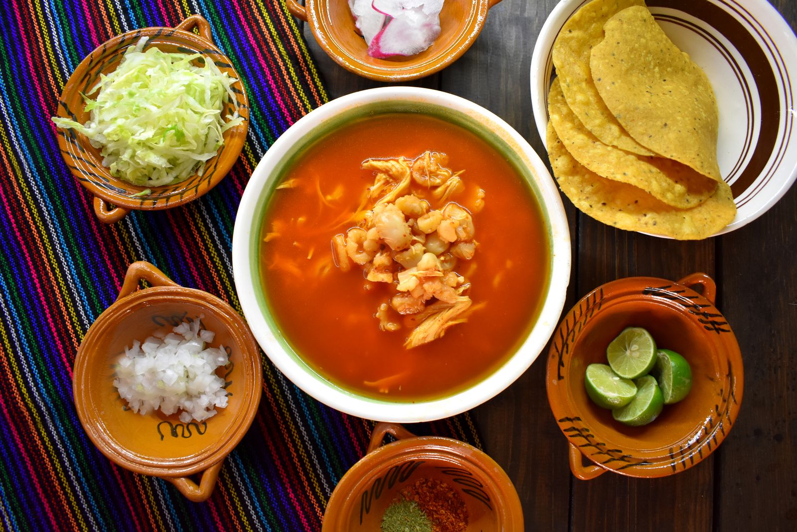 Tomato tortilla soup with toppings on a colorful table