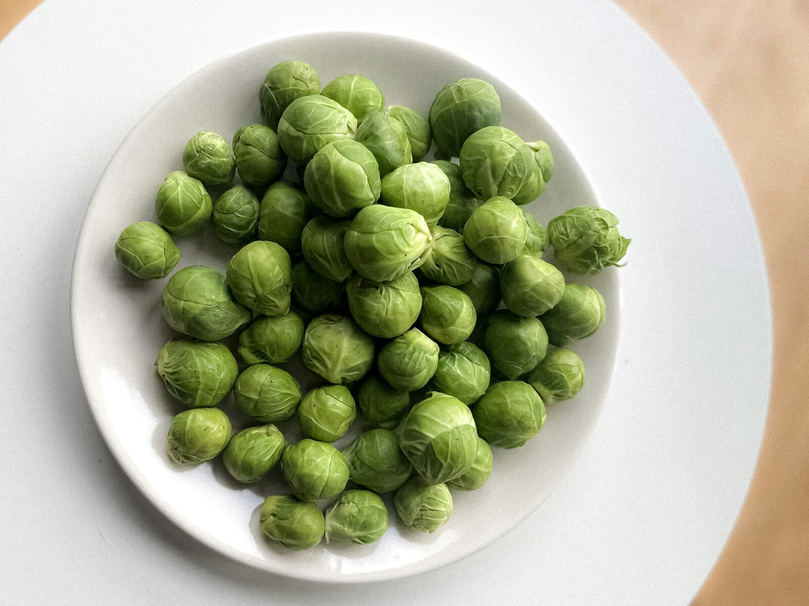 Brussels sprouts on a white plate ready for roasting