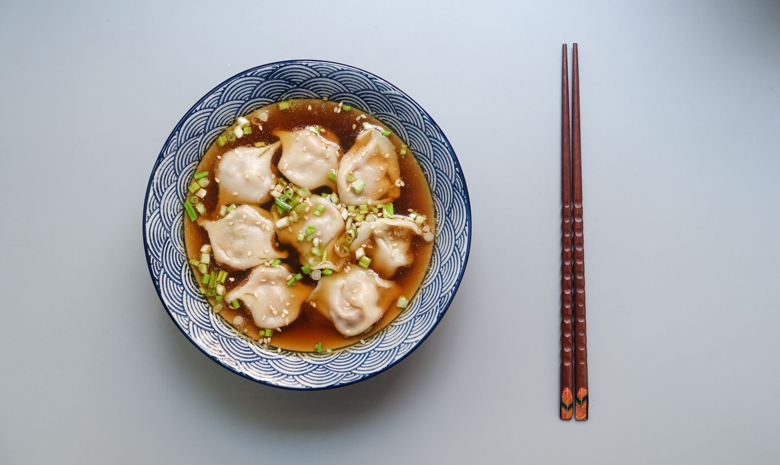 Dumpling soup in a bowl with chopsticks