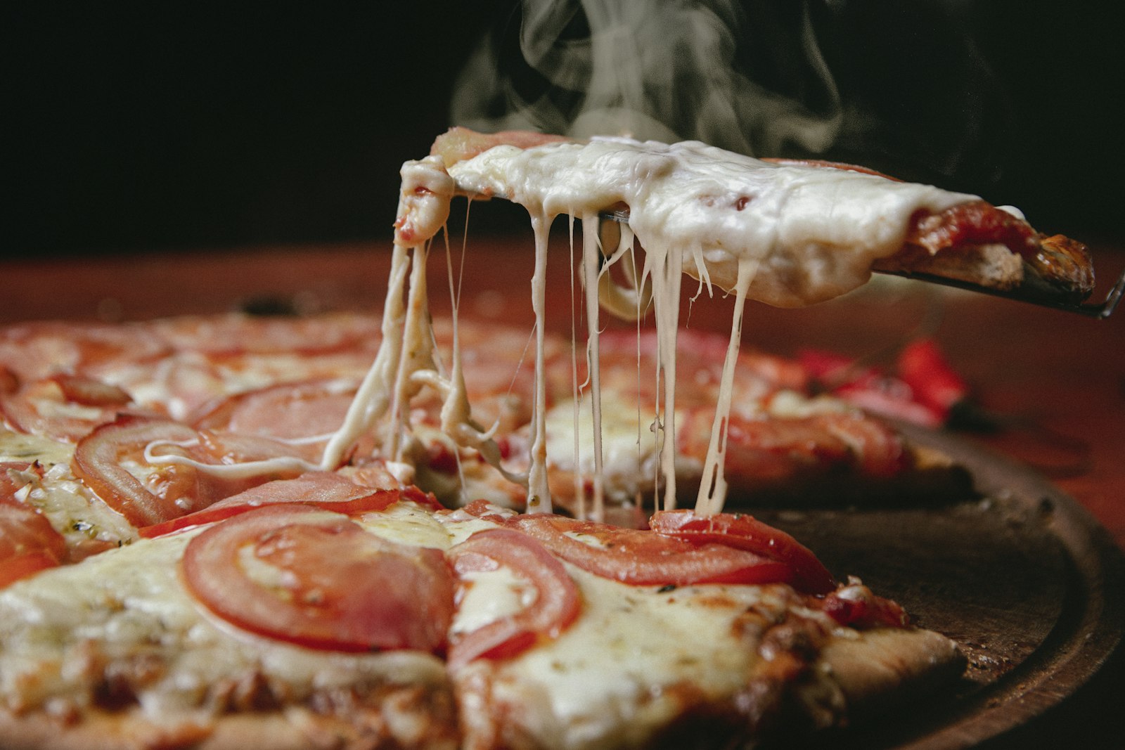 A cheesy pizza slice with a long cheese pull
