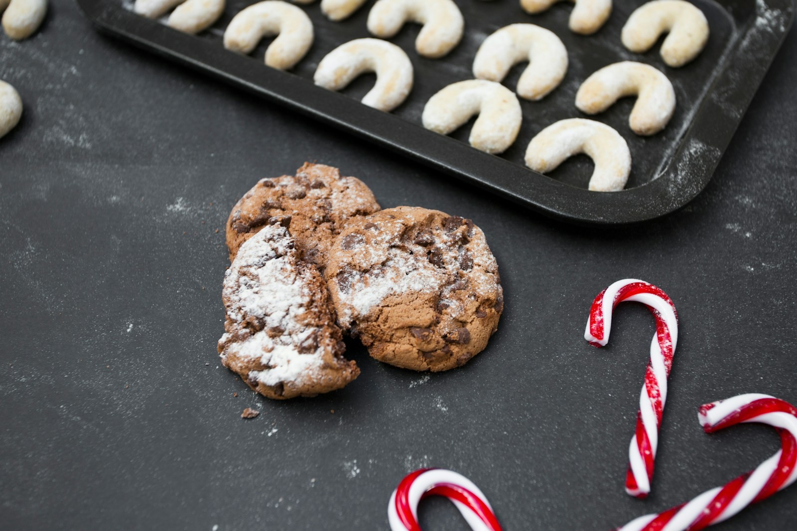 Chocolate peppermint crinkles dusted with powdered sugar next to red and white candy canes