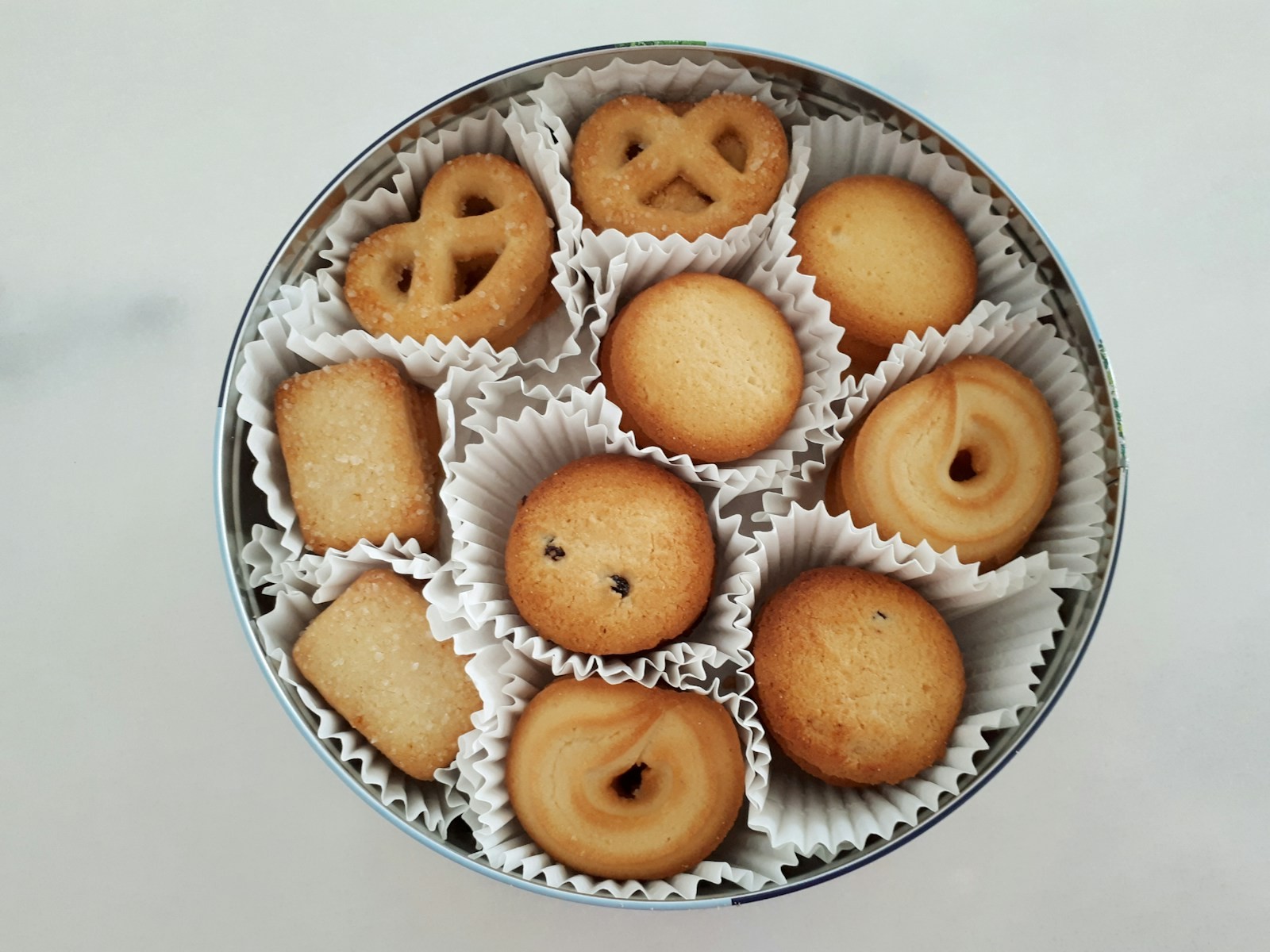 Homemade holiday treats packed in paper liners inside a round metal tin