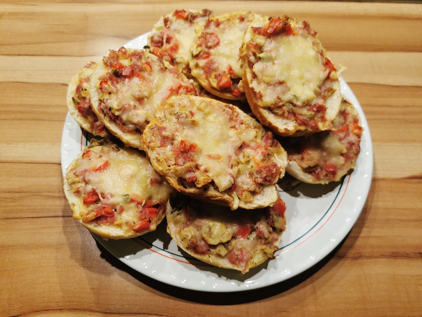 Pizza flavored dinners from Germany: plate of halved rolls baked with tomato, ham, melted cheese and herbs