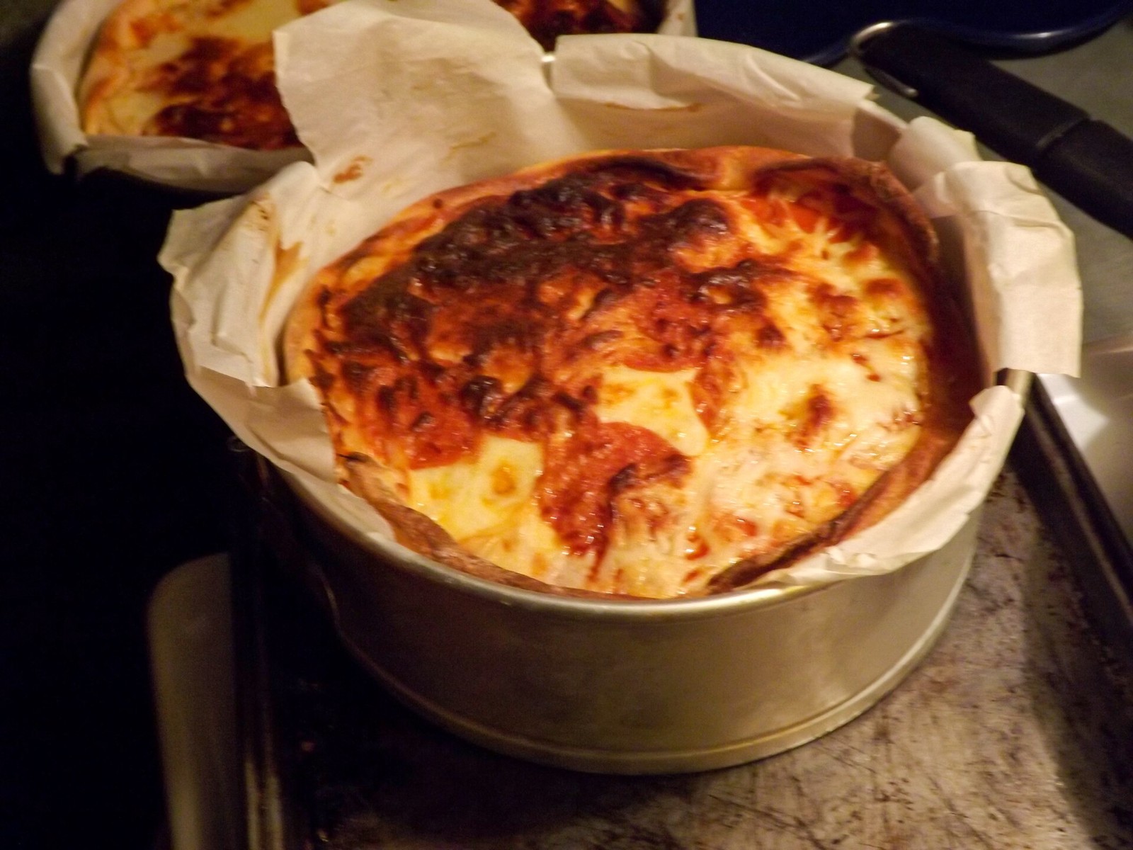 Tall layered pizza casserole baked in a round pan with a golden browned cheese top