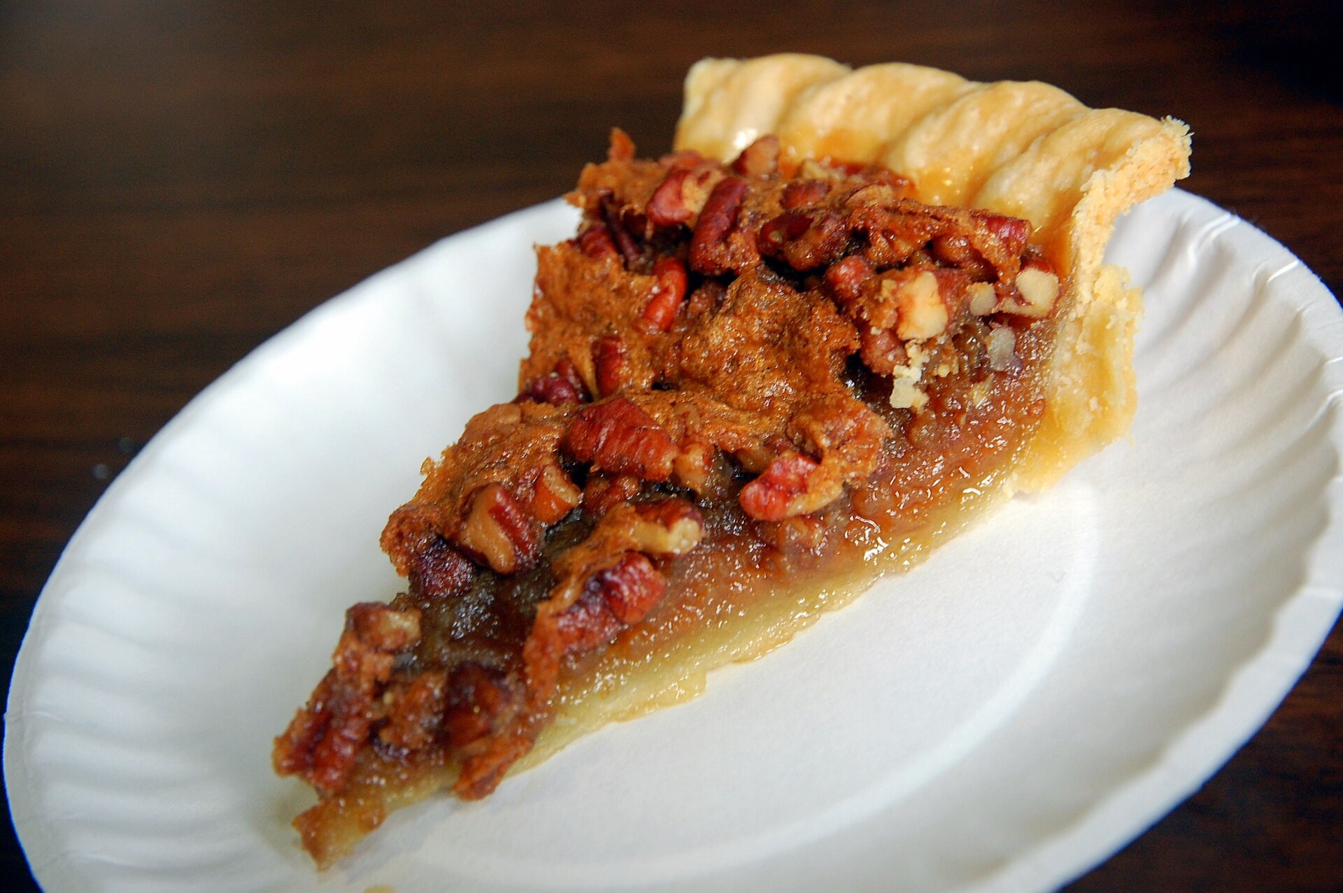 Slice of classic pecan pie with a flaky crust on a white plate