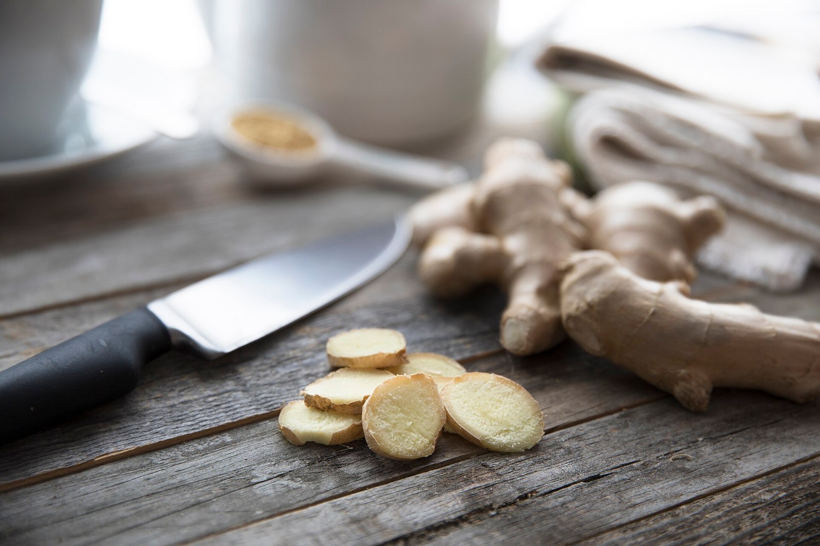 Fresh ginger root with slices on a dark board