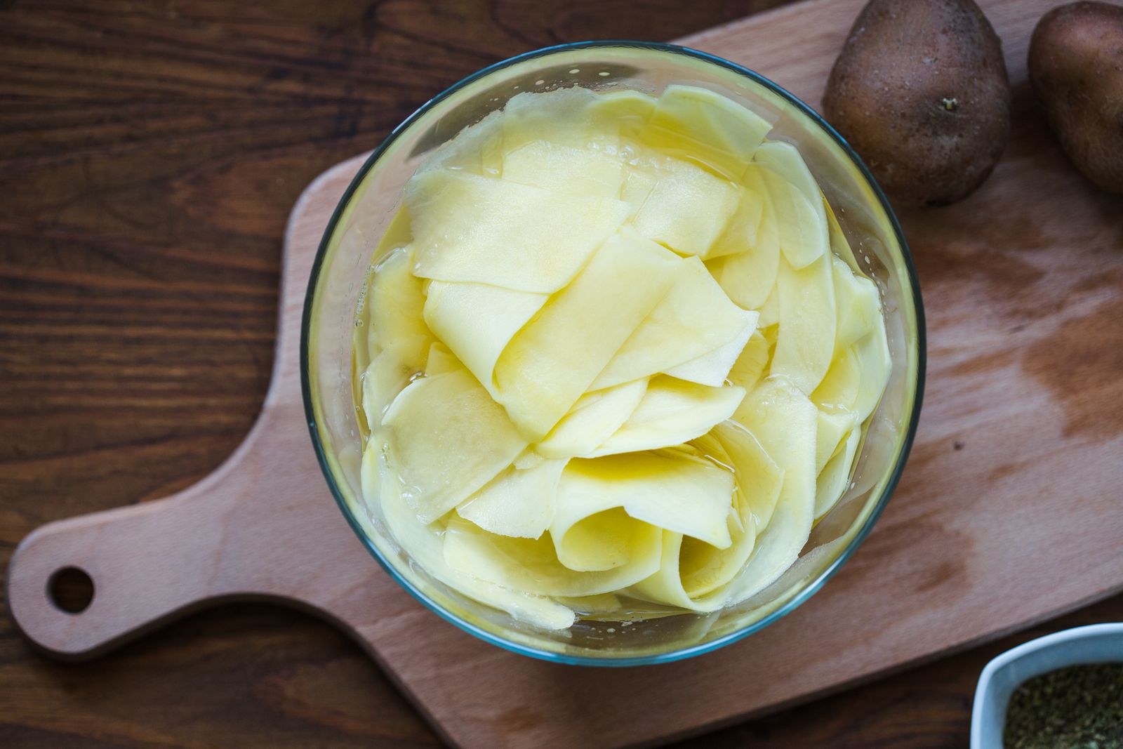 Sliced raw potatoes kept in a bowl of cold water