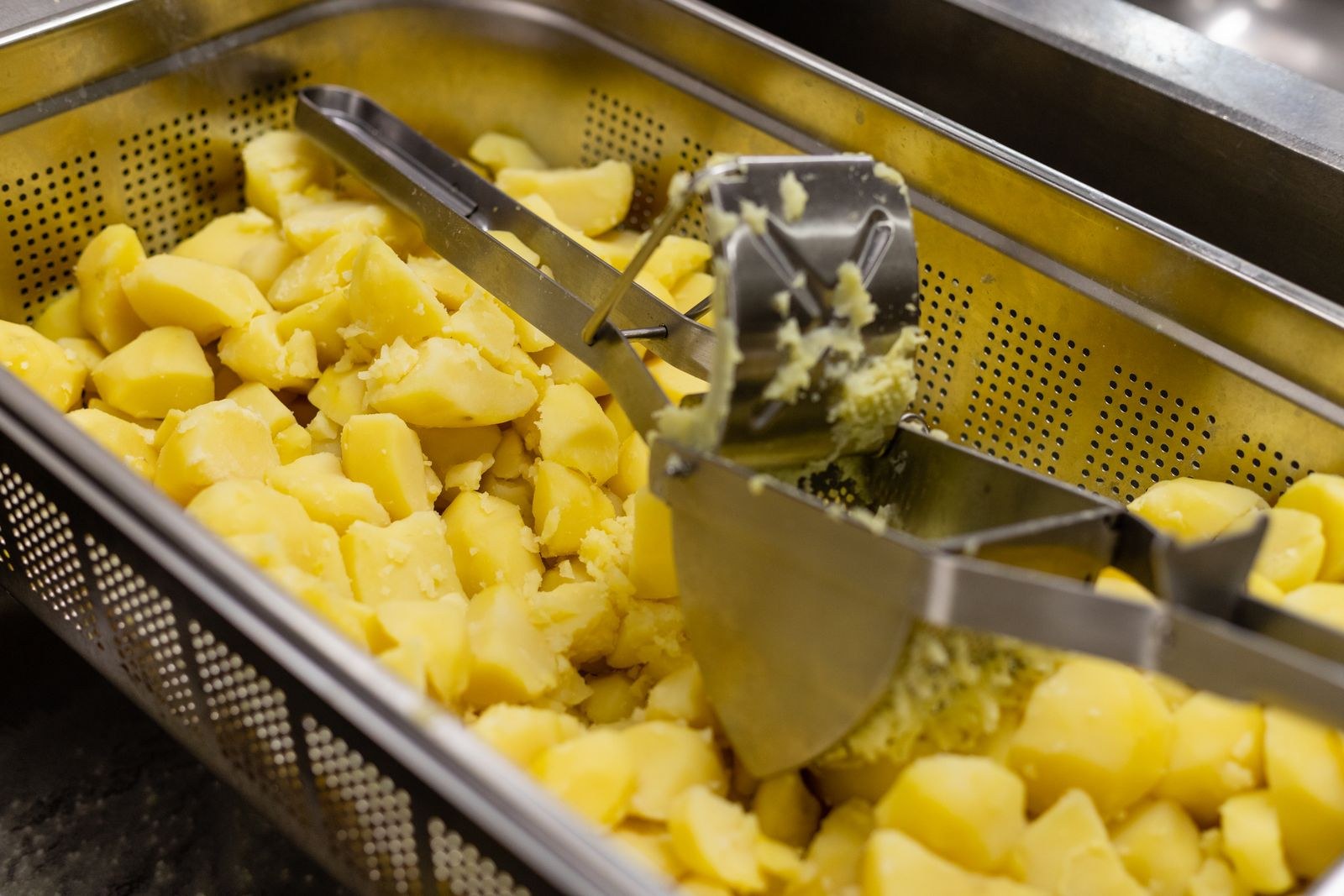 Potato hacks: boiled potatoes being mashed with a potato ricer