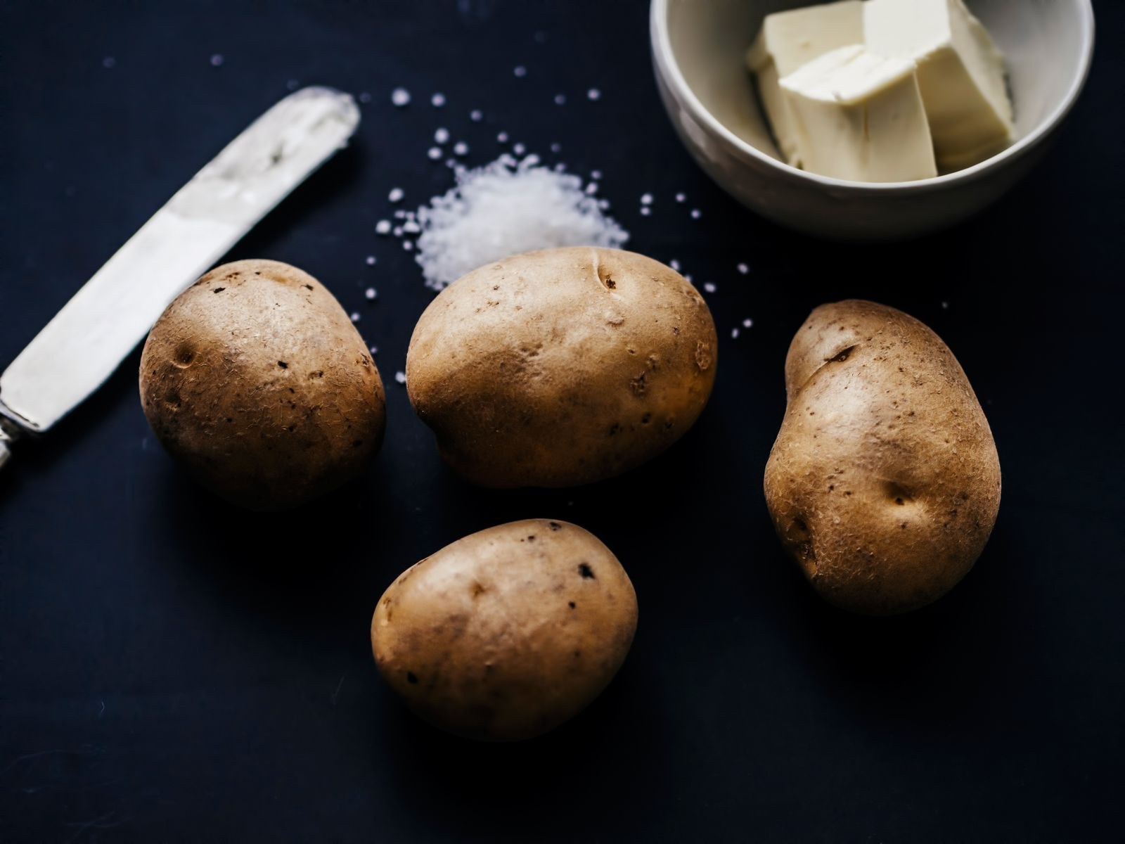 Russet potatoes with coarse salt and butter for crispy baked skins