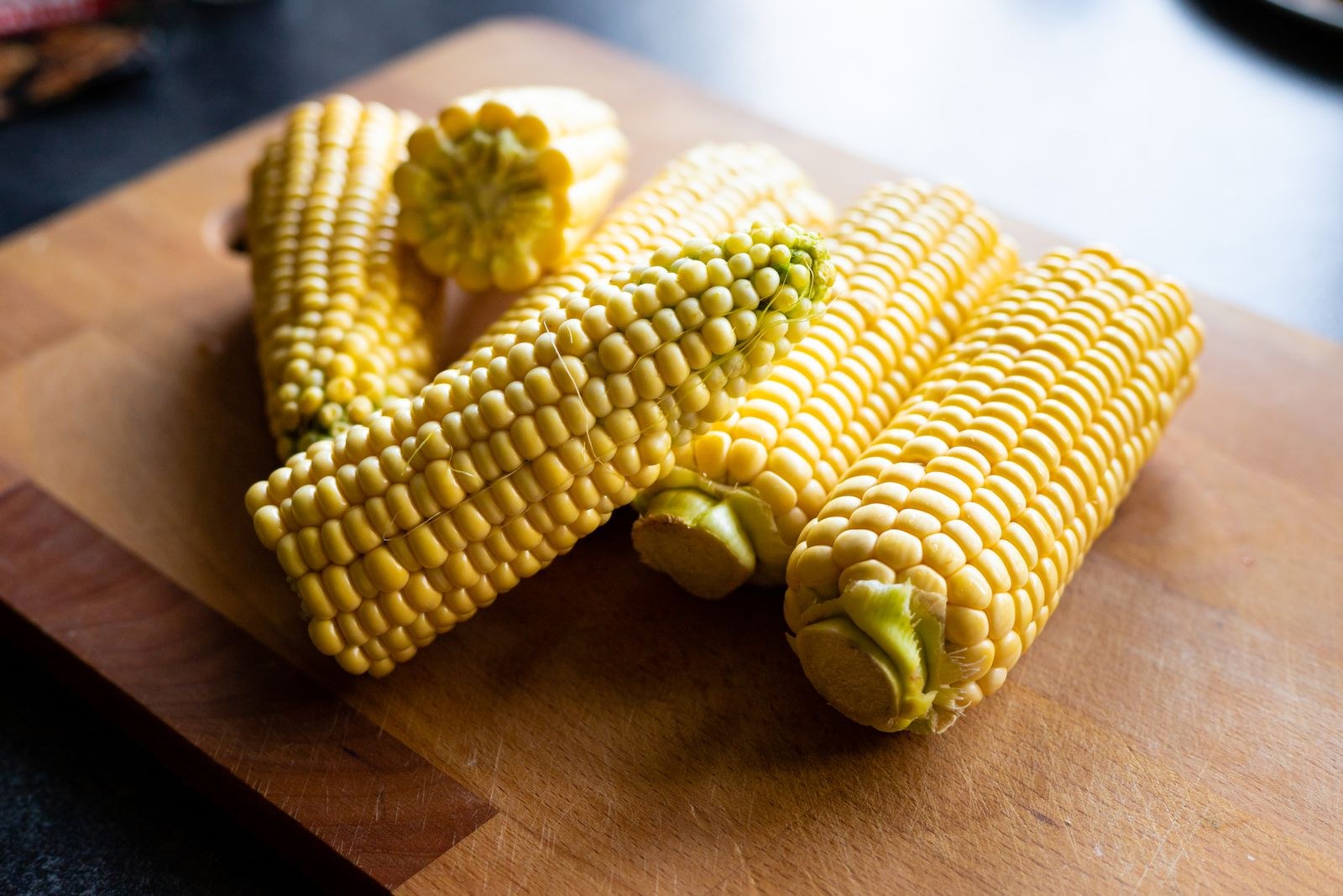 Fresh corn on the cob on a wooden board