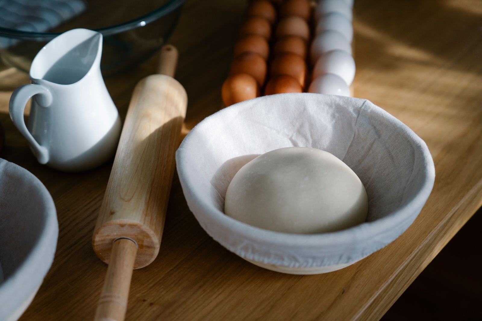 Bread dough in a bowl beside a rolling pin