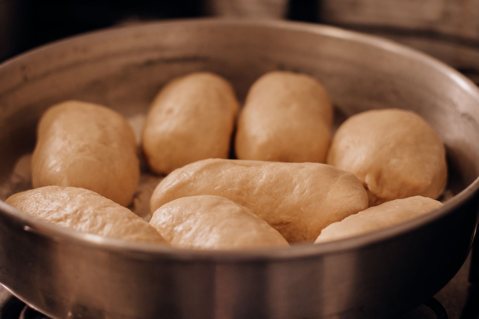 Soft dinner rolls rising in a pan