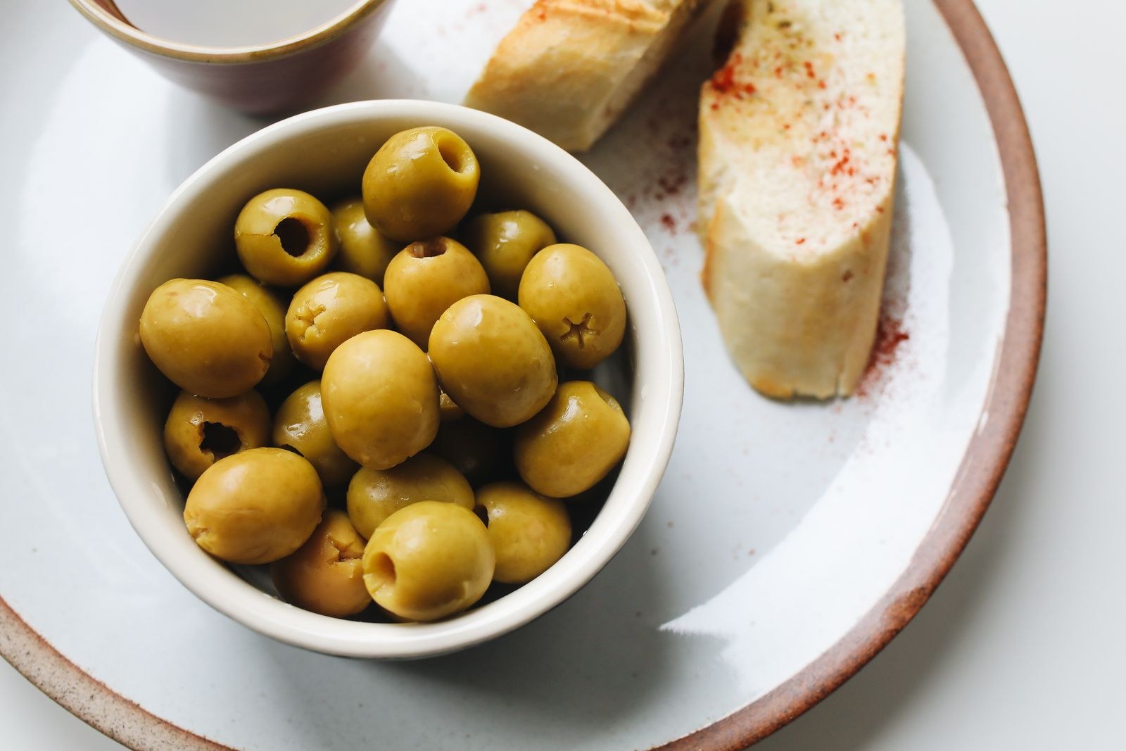 Bowl of green olives with bread